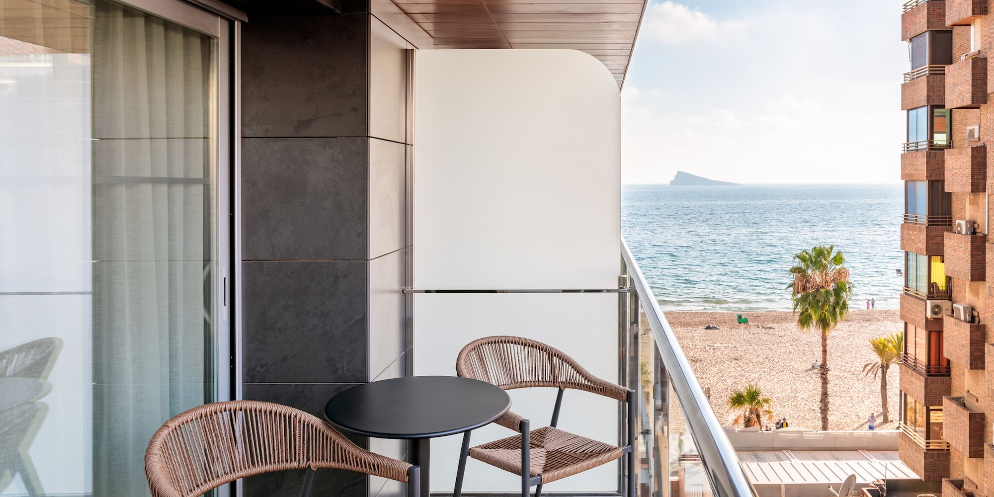 a balcony with chairs and a table overlooking the ocean