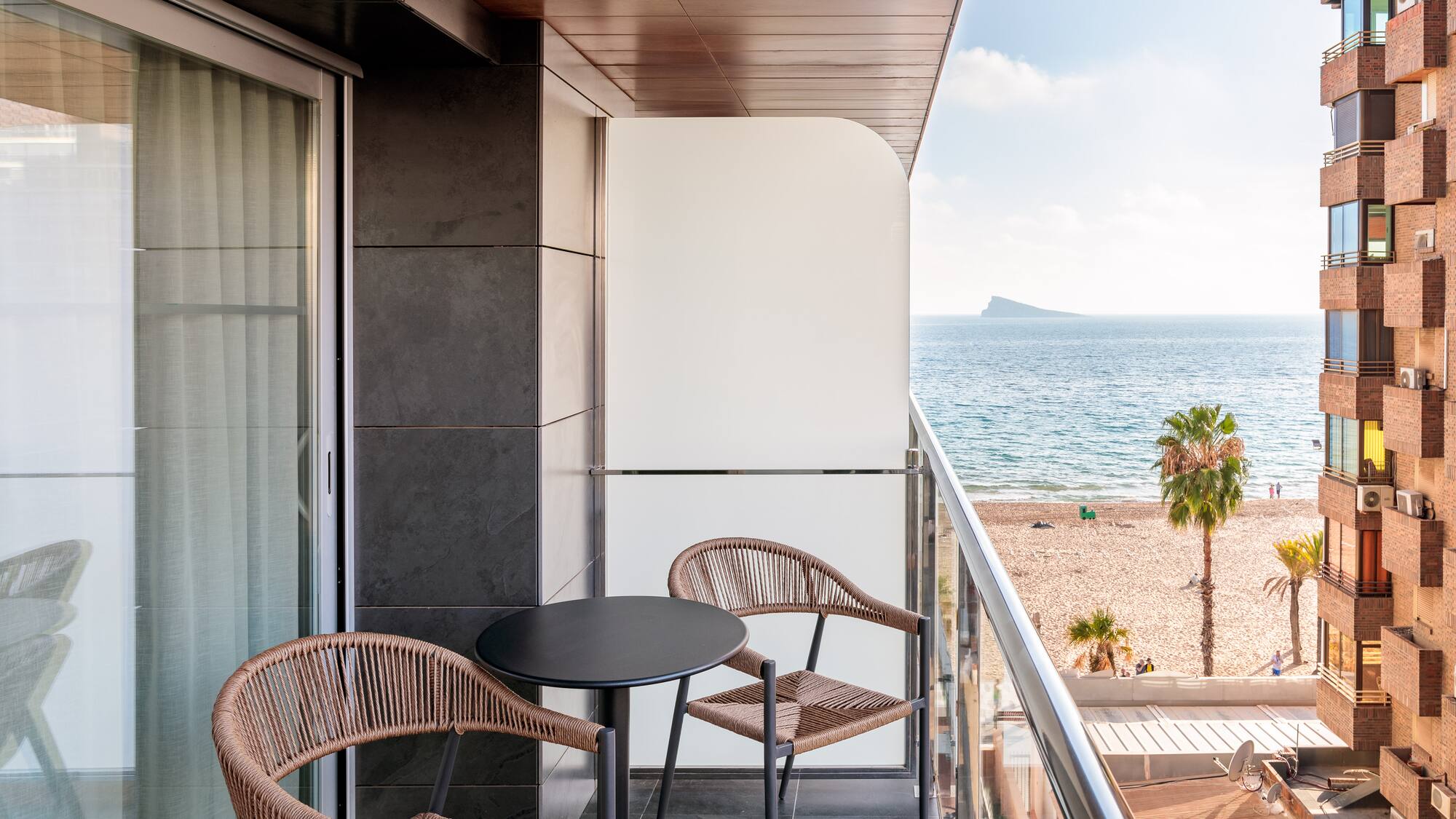 a balcony with chairs and a table overlooking the ocean