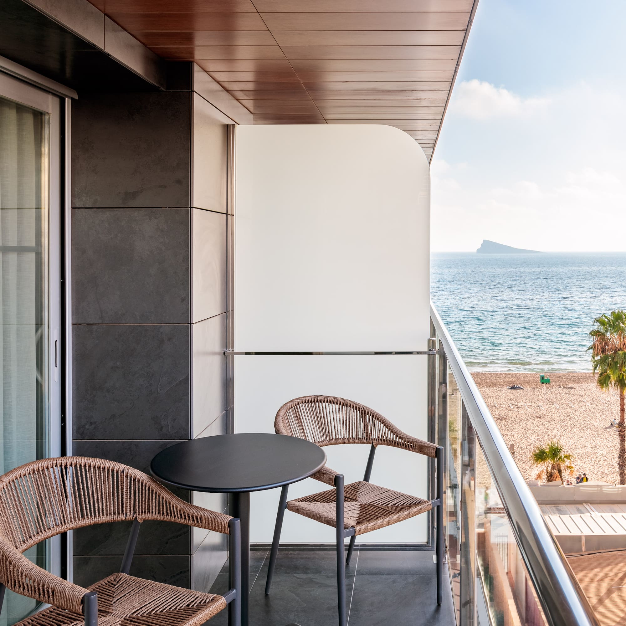 a balcony with chairs and a table overlooking the ocean