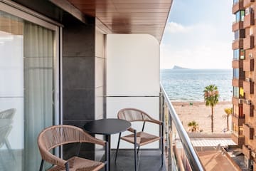 a balcony with chairs and a table overlooking the ocean