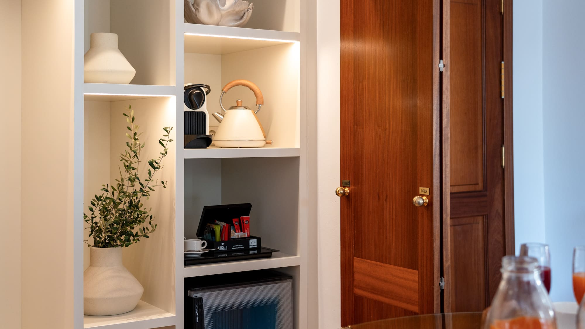 a white shelves with a tea kettle and a plant in a room