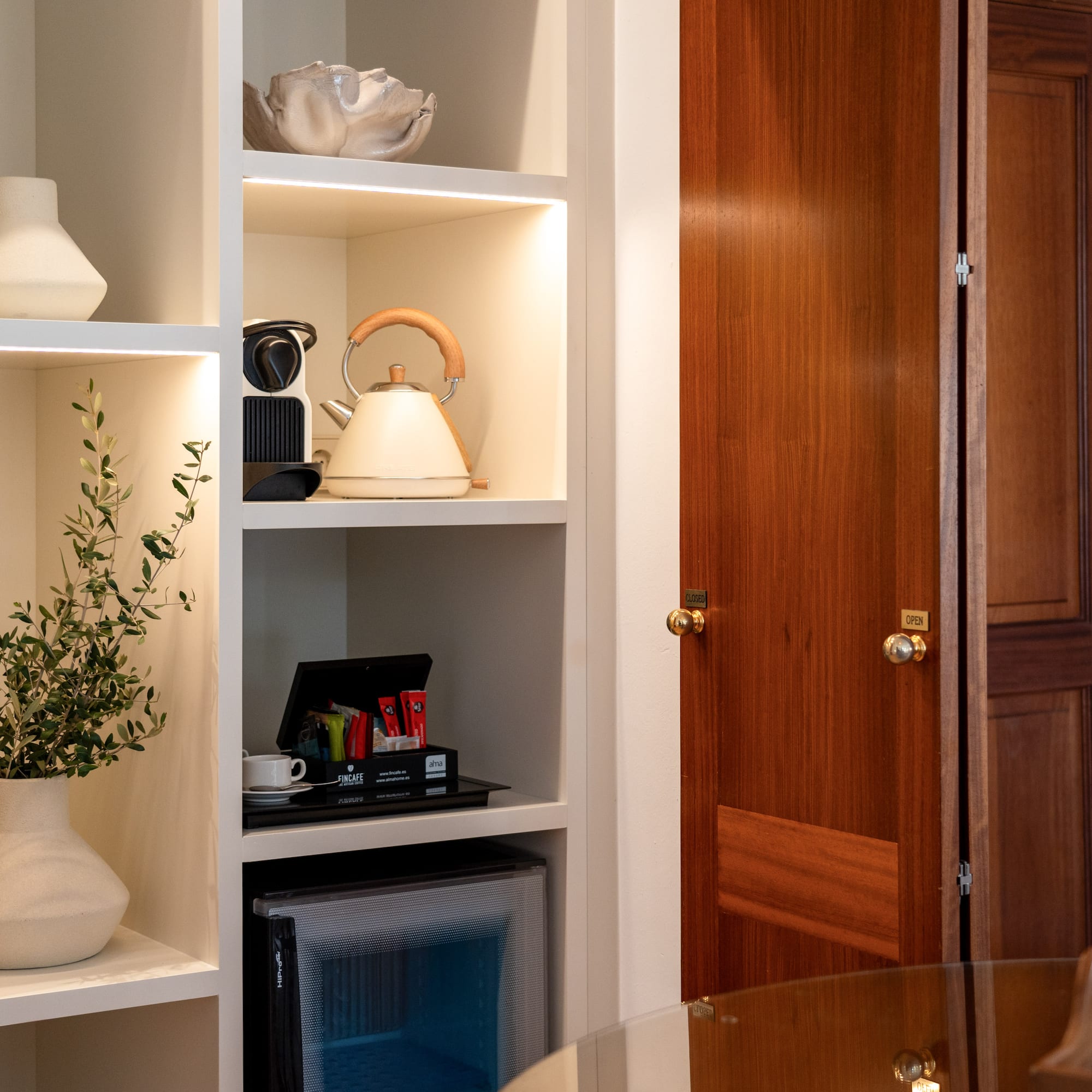 a white shelves with a tea kettle and a plant in a room