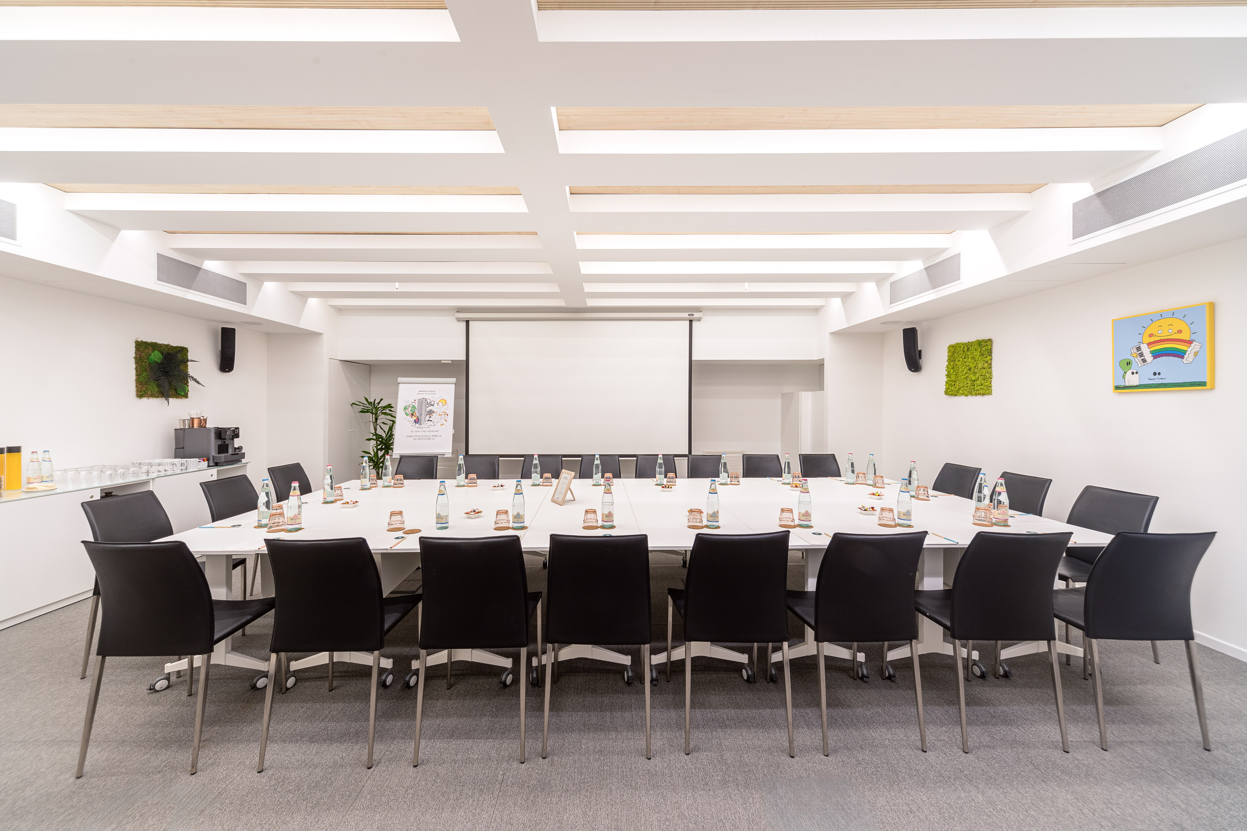 Modern conference room with U-shaped table, projector, black chairs.