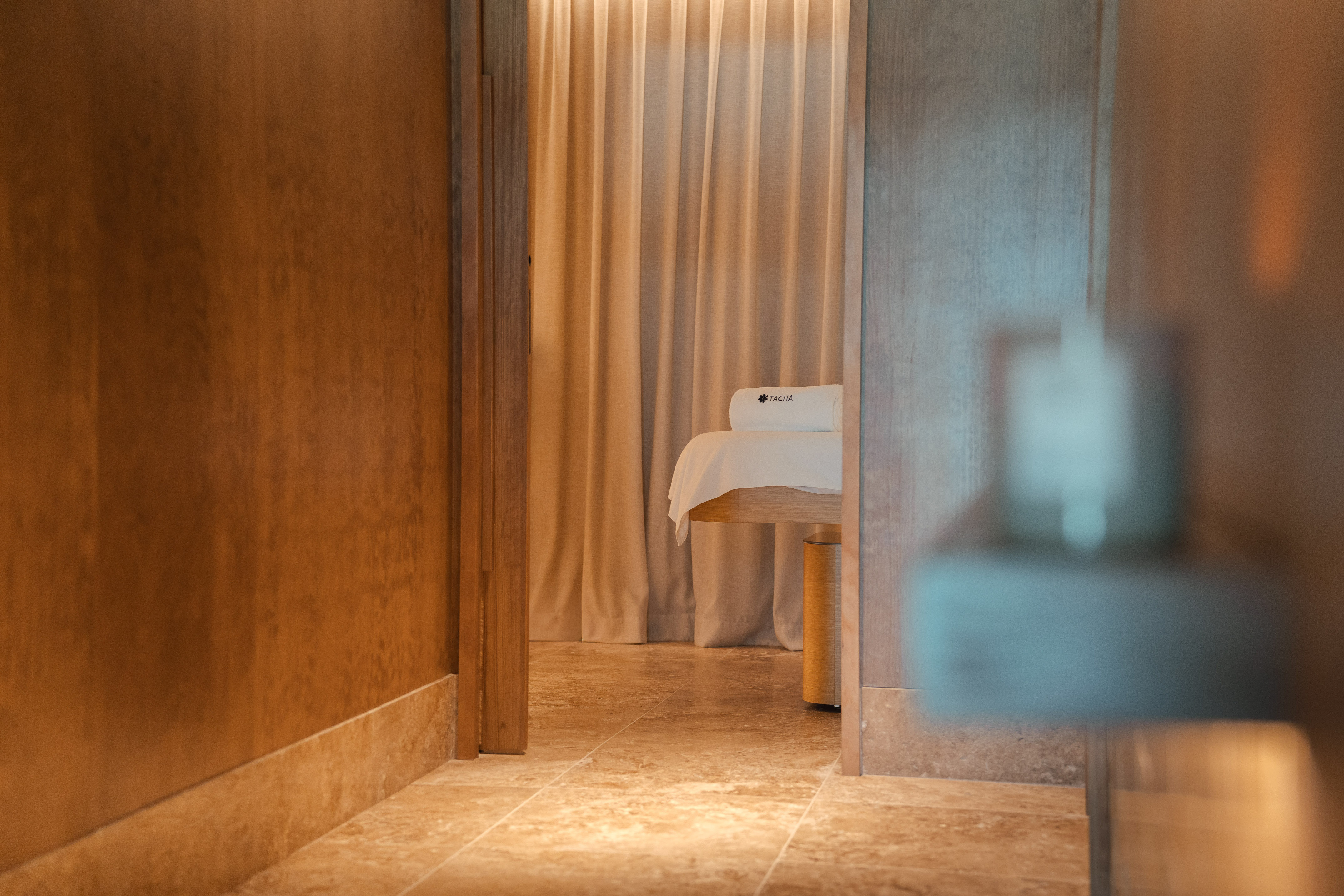 Tranquil spa room entry with massage table and TACHA towel.