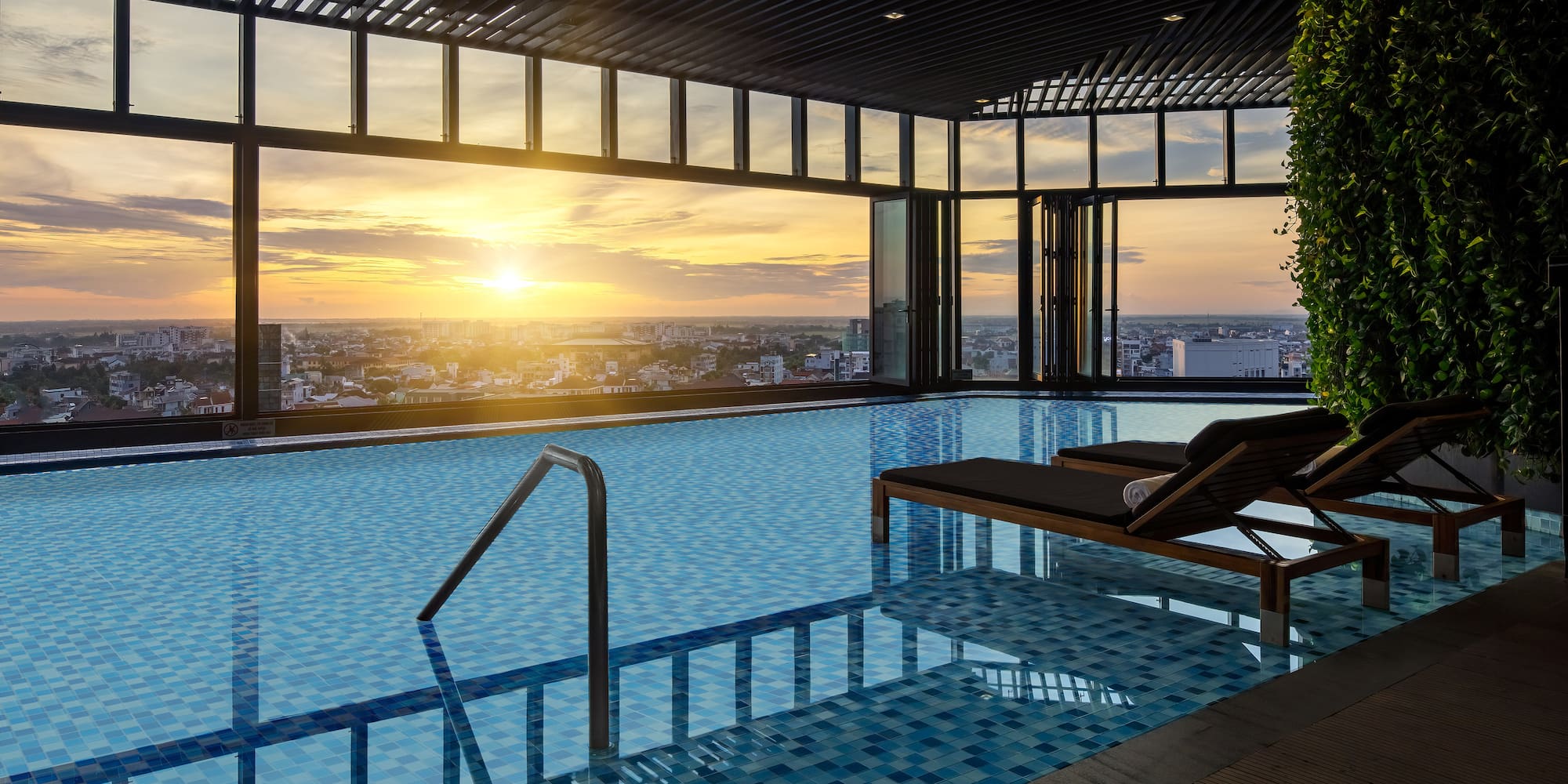 a pool with a view of a city and a sunset