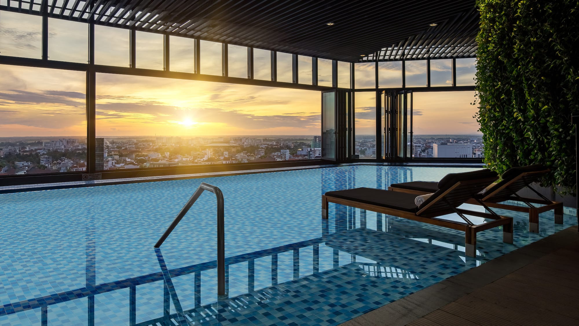 a pool with a view of a city and a sunset