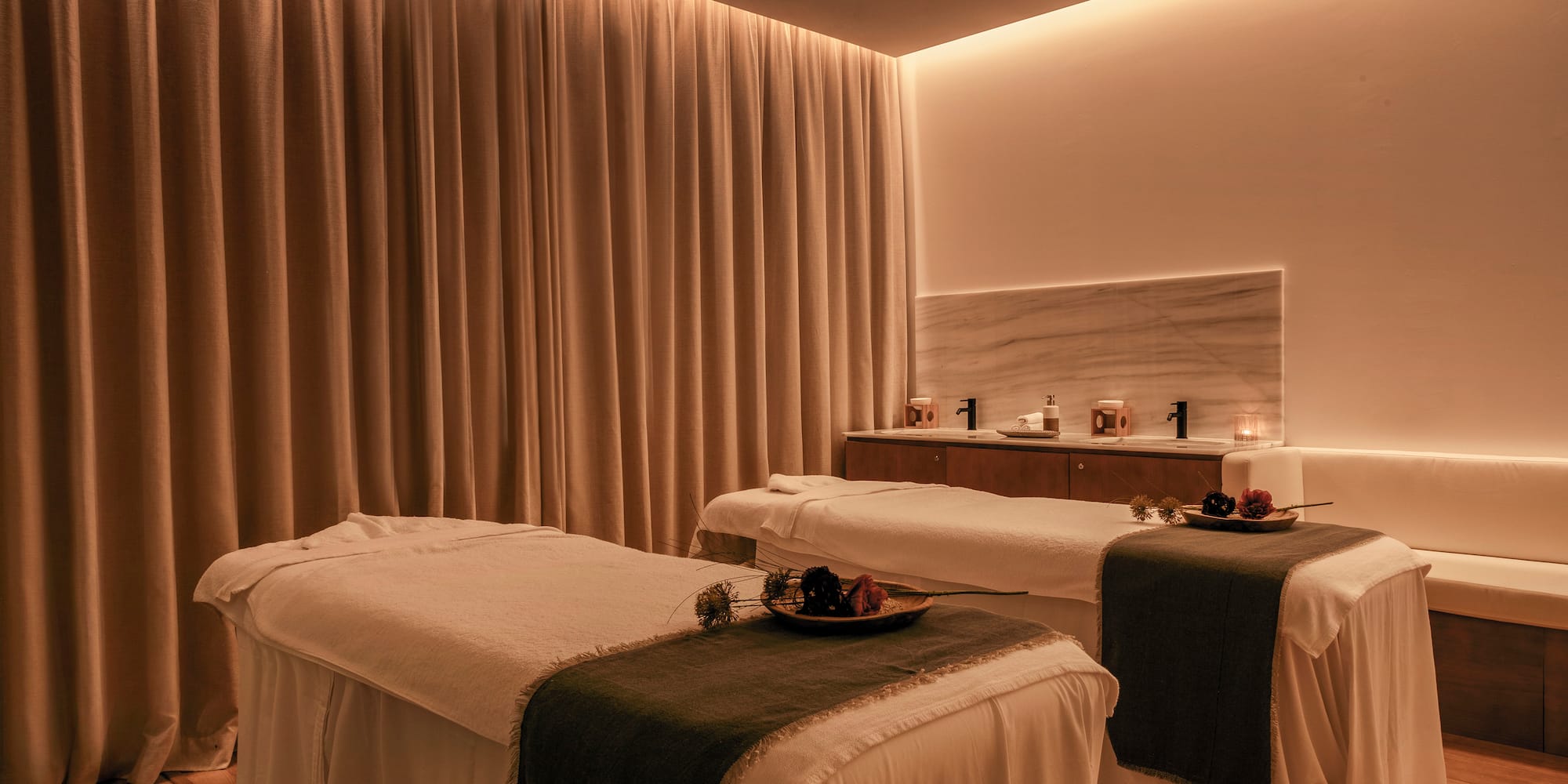 a massage room with white beds and candles