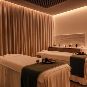 a massage room with white beds and candles
