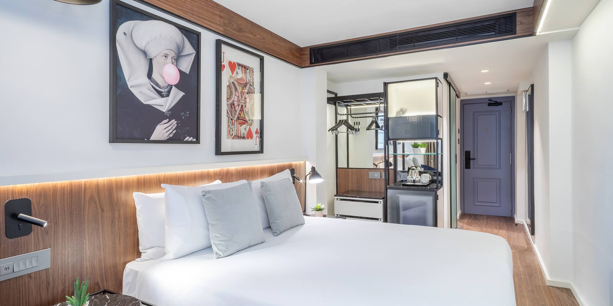 a bed with white sheets and pillows in a room with a wood floor