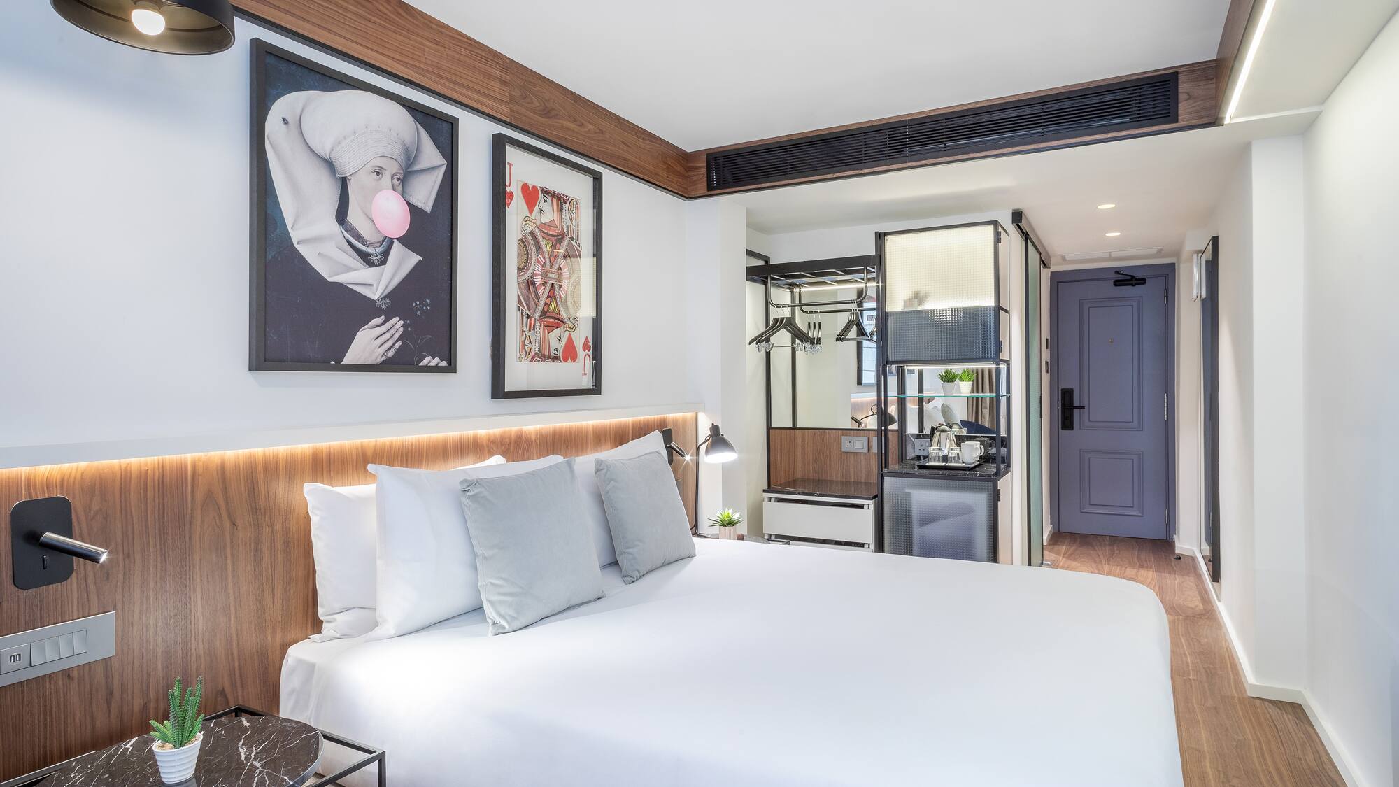 a bed with white sheets and pillows in a room with a wood floor