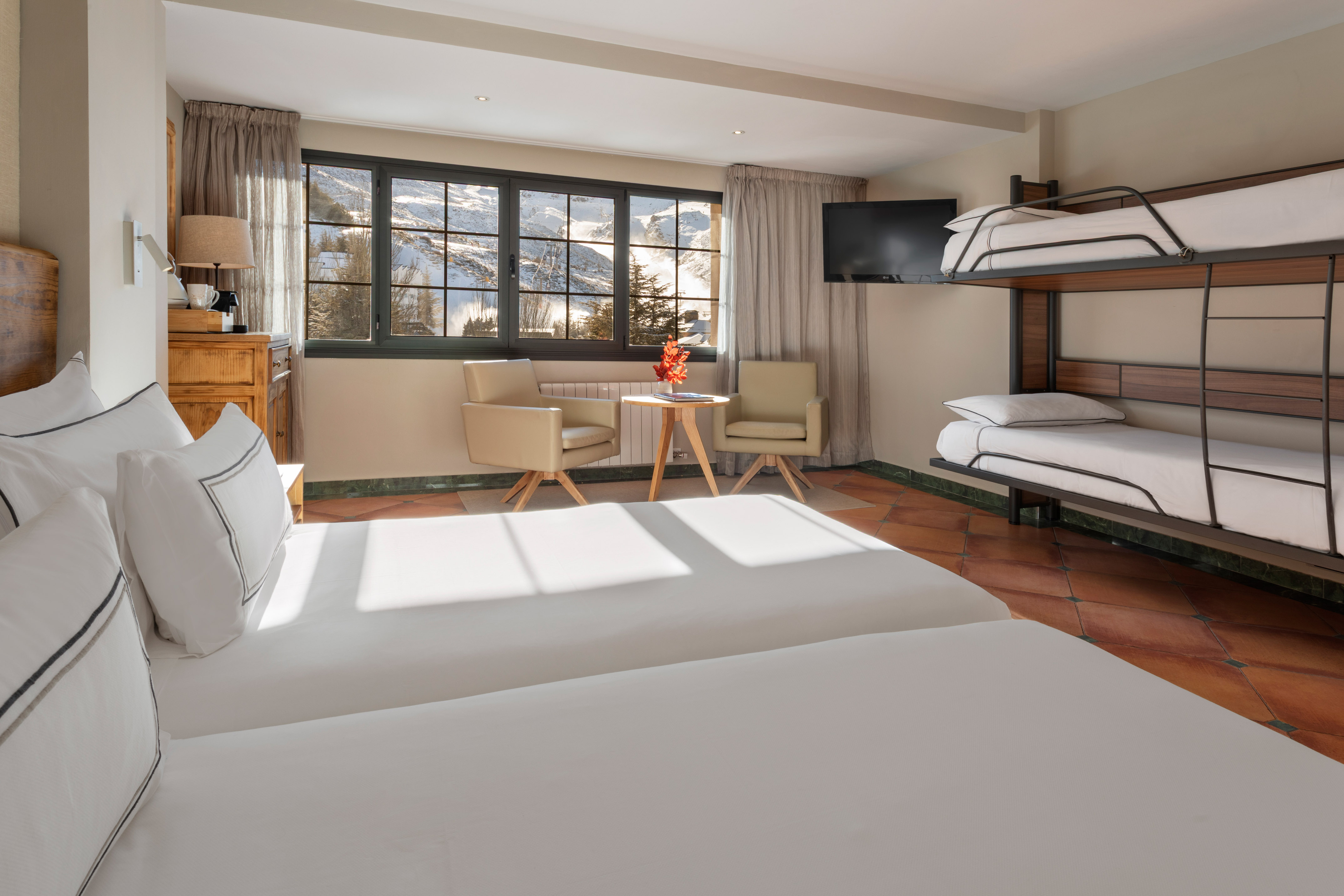 Ski resort room with twin and bunk beds, snowy mountain view.