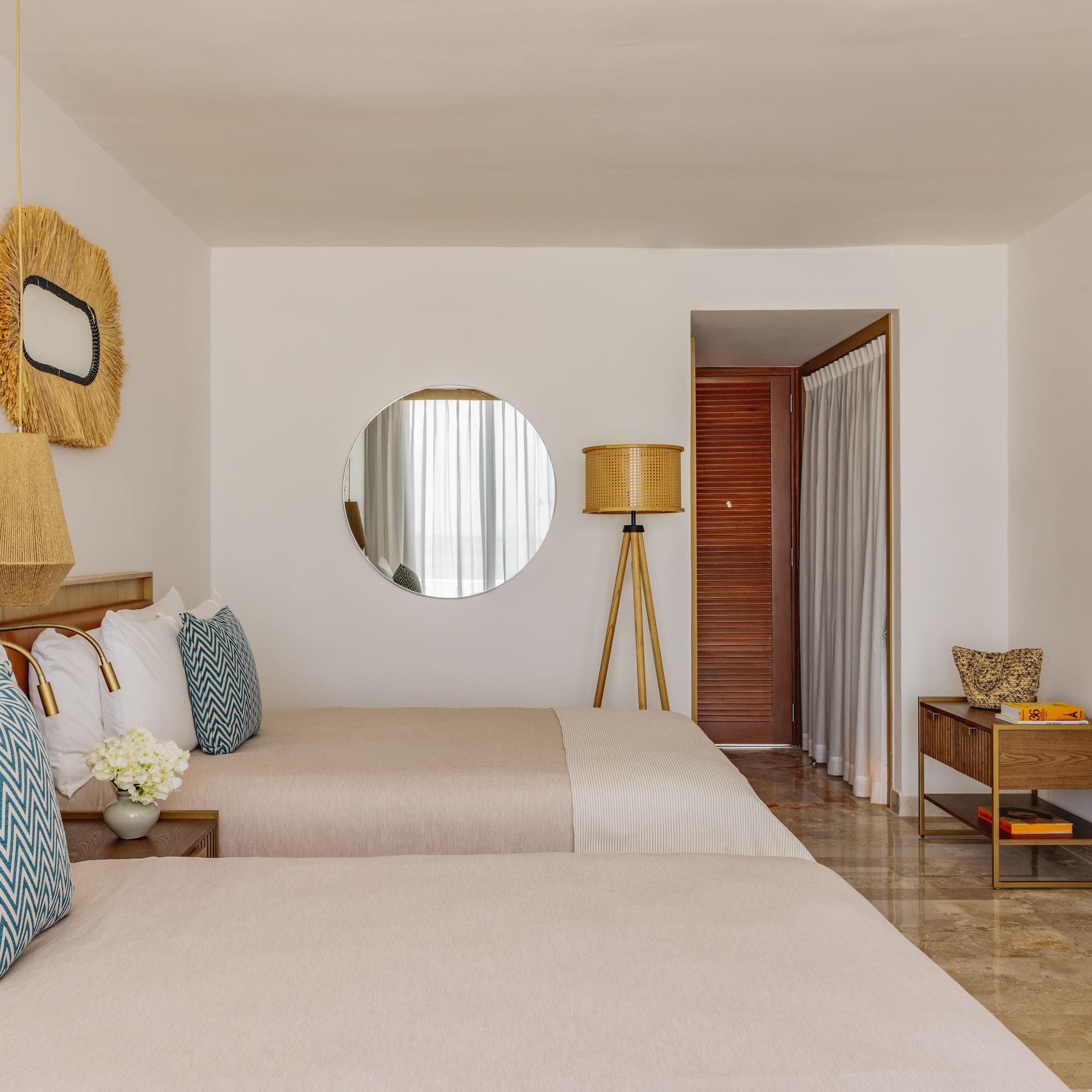Modern hotel room with two twin beds, natural decor, and minimalist design.