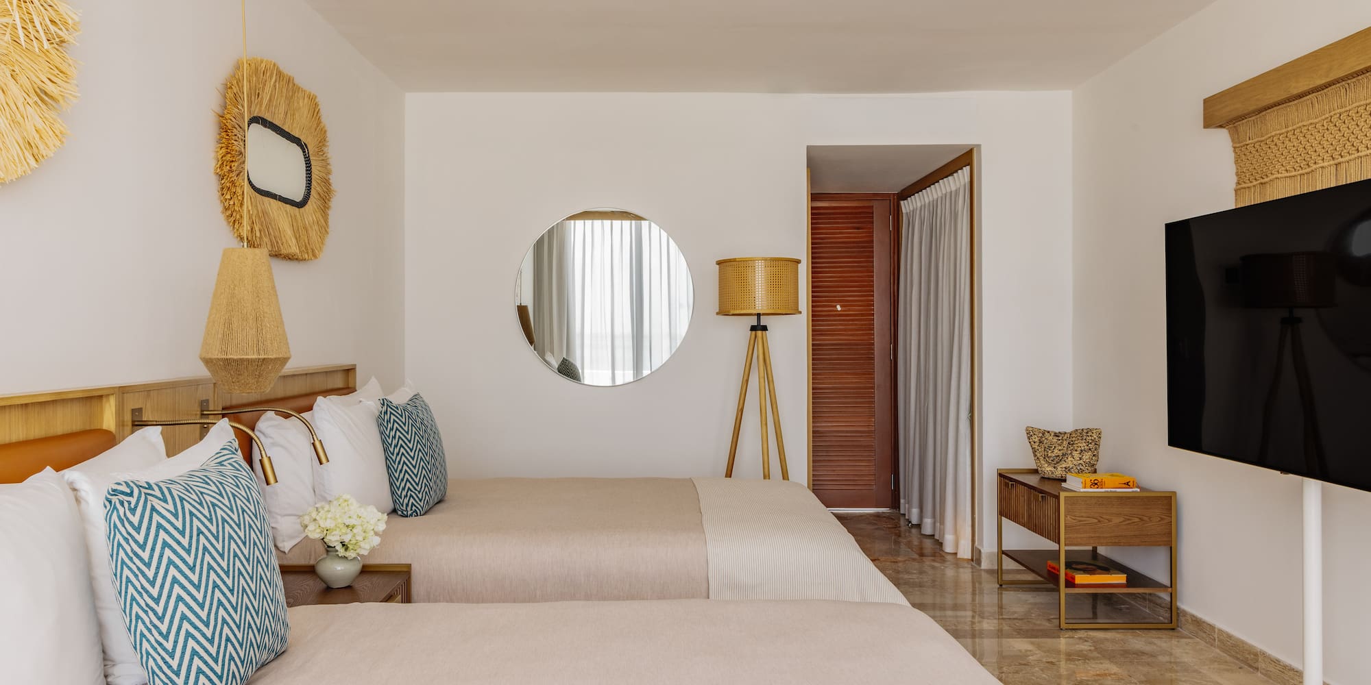 Bright tropical hotel room with two twin beds, straw decor, and modern amenities.