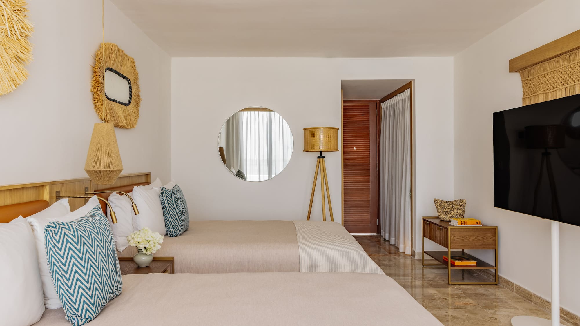 Bright tropical hotel room with two twin beds, straw decor, and modern amenities.