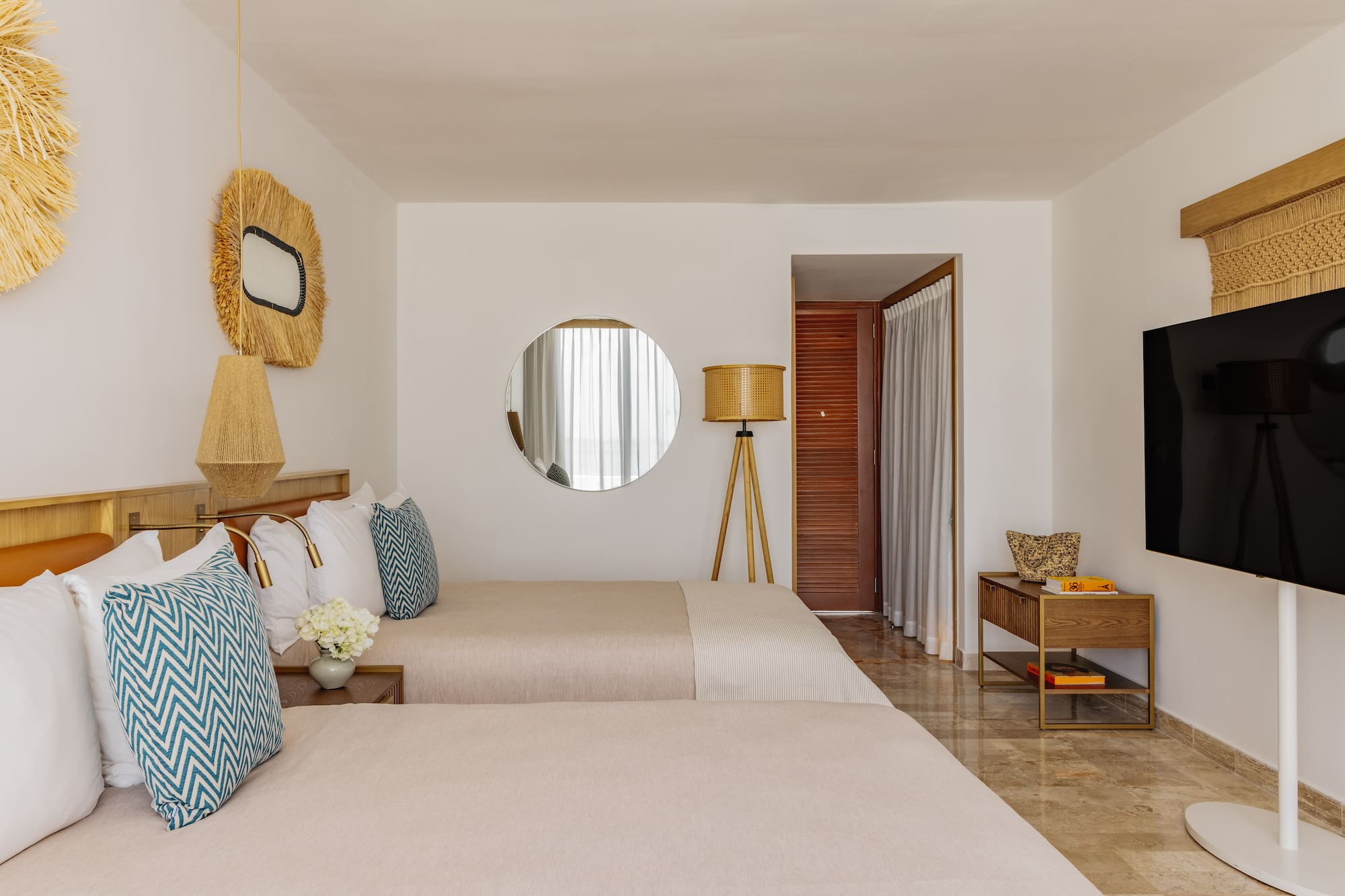 Bright tropical hotel room with two twin beds, straw decor, and modern amenities.