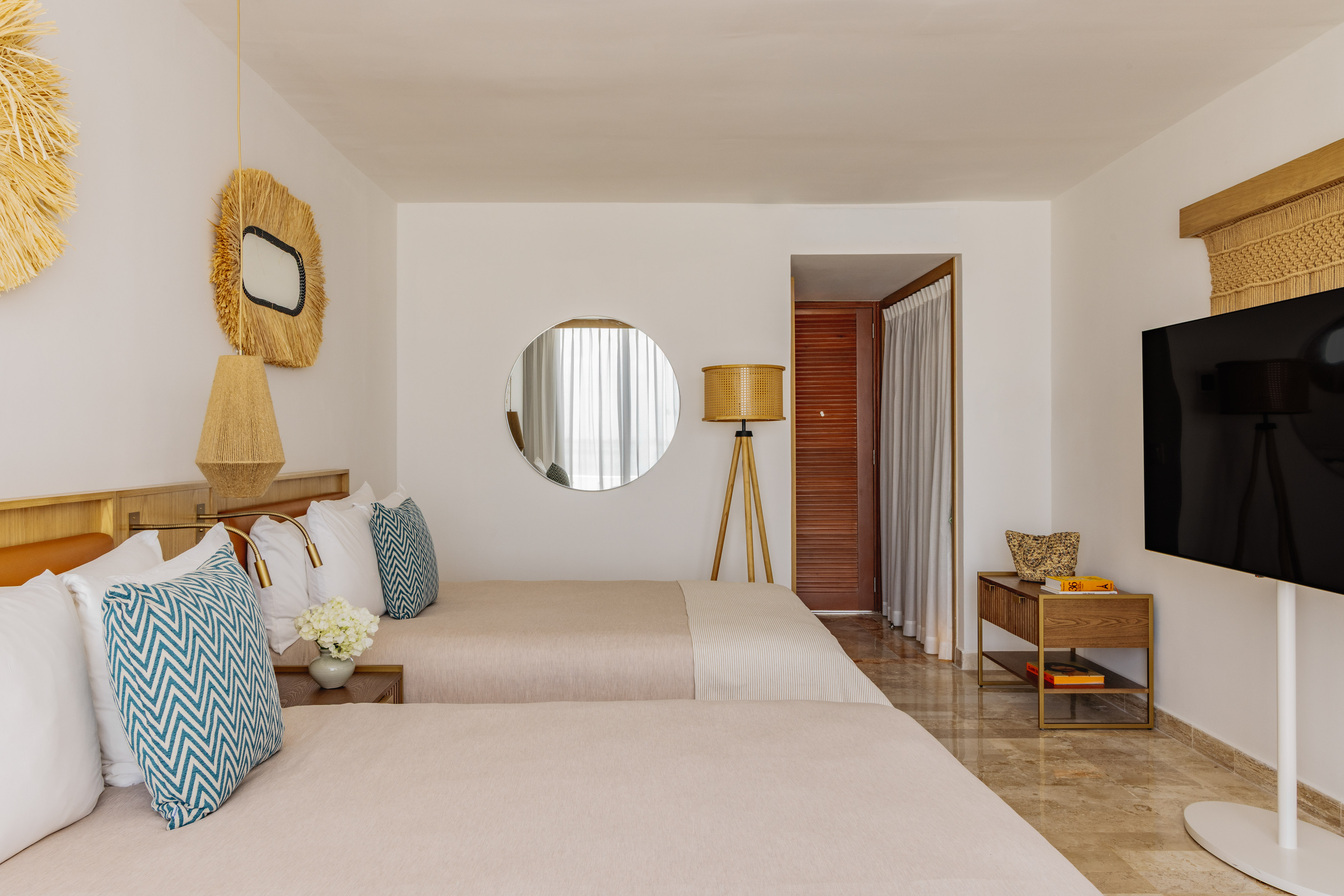 Bright tropical hotel room with two twin beds, straw decor, and modern amenities.