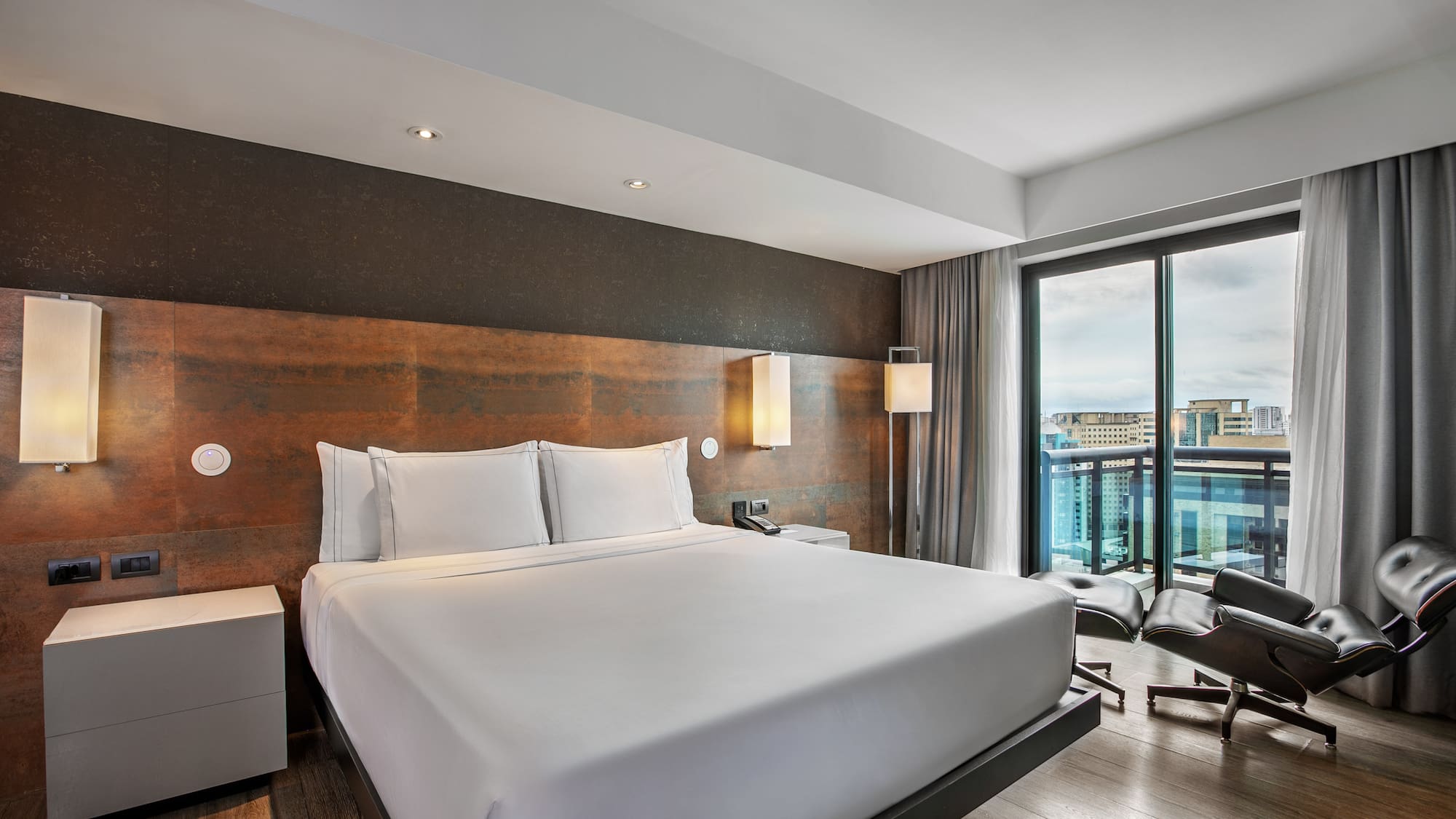 Quarto de hotel moderno com cama king-size, cabeceira rústica e grande janela. - Grand Premium com Varanda - Meliá Ibirapuera, São Paulo