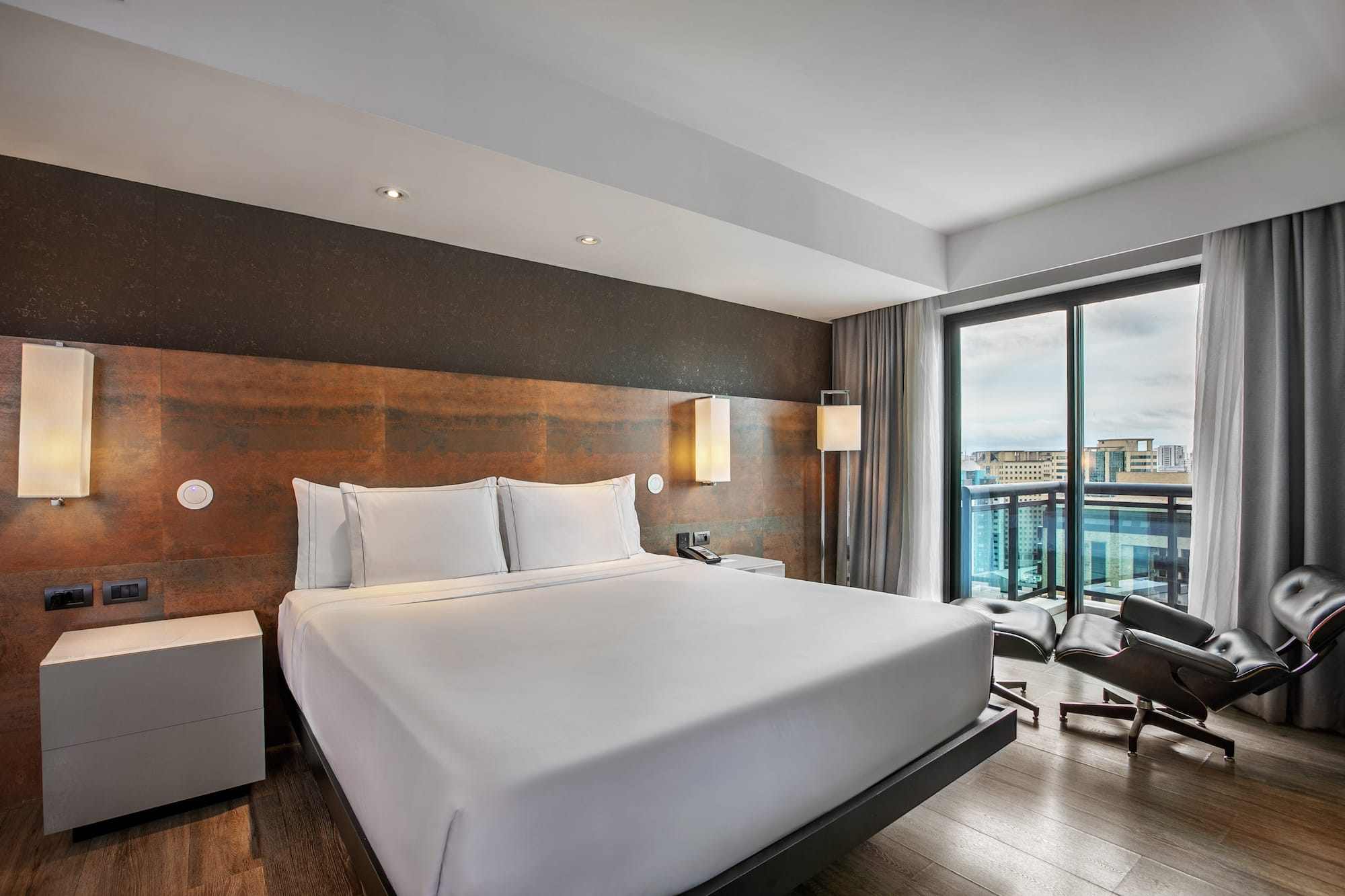 Quarto de hotel moderno com cama king-size, cabeceira rústica e grande janela. - Grand Premium com Varanda - Meliá Ibirapuera, São Paulo