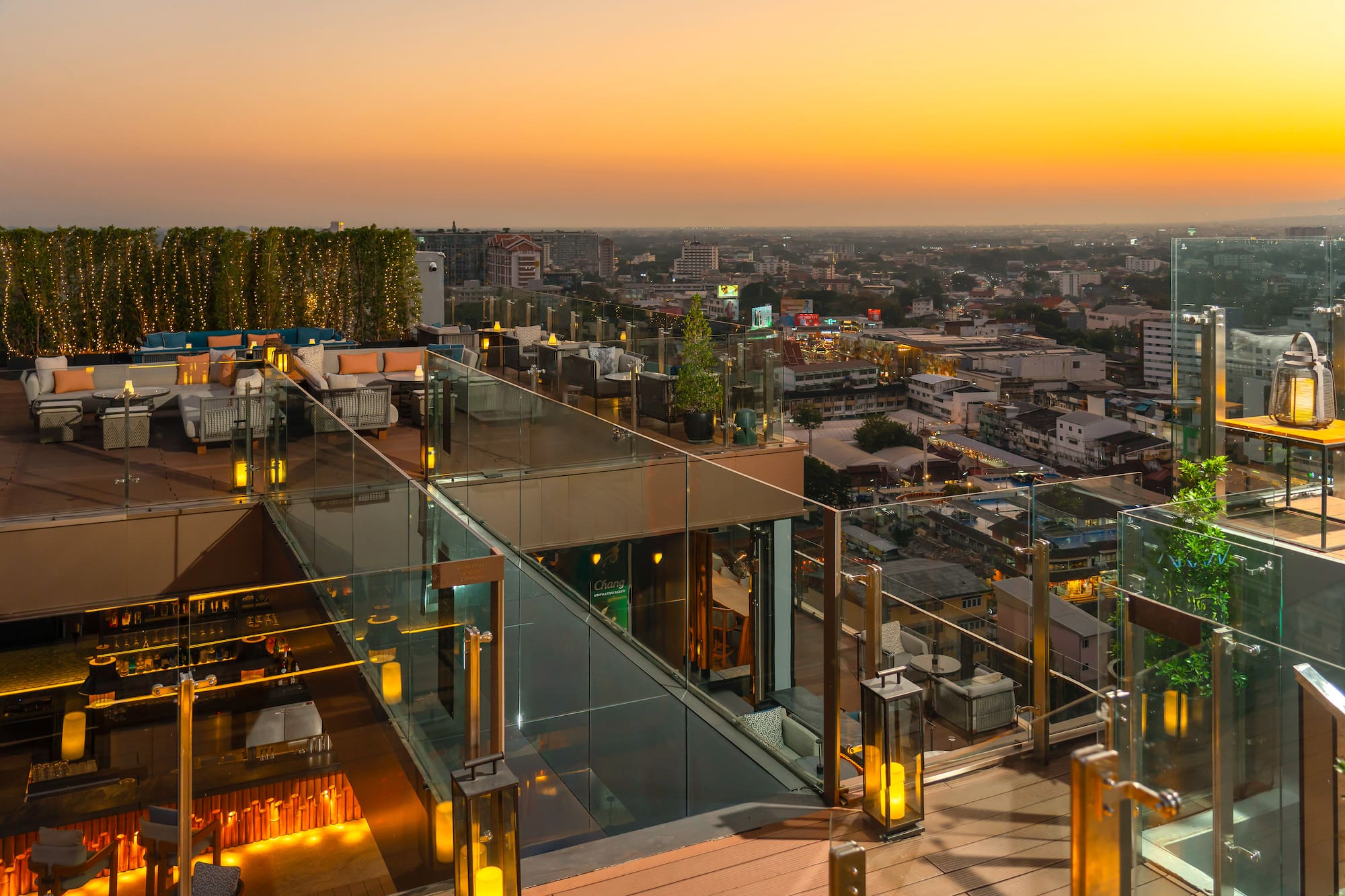 Rooftop bar with sunset city view, outdoor lounge, and ambient lighting.