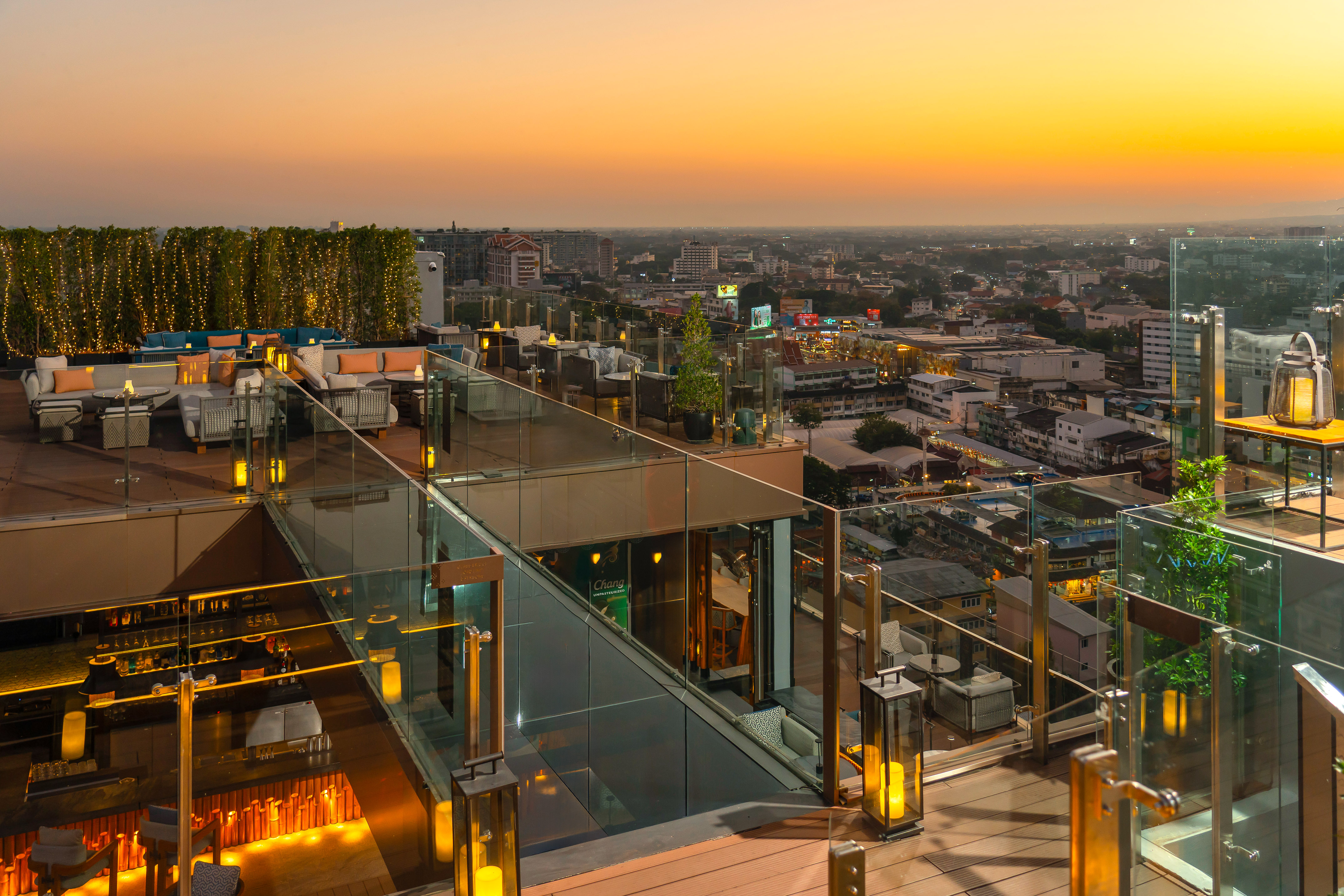 Rooftop bar with sunset city view, outdoor lounge, and ambient lighting.