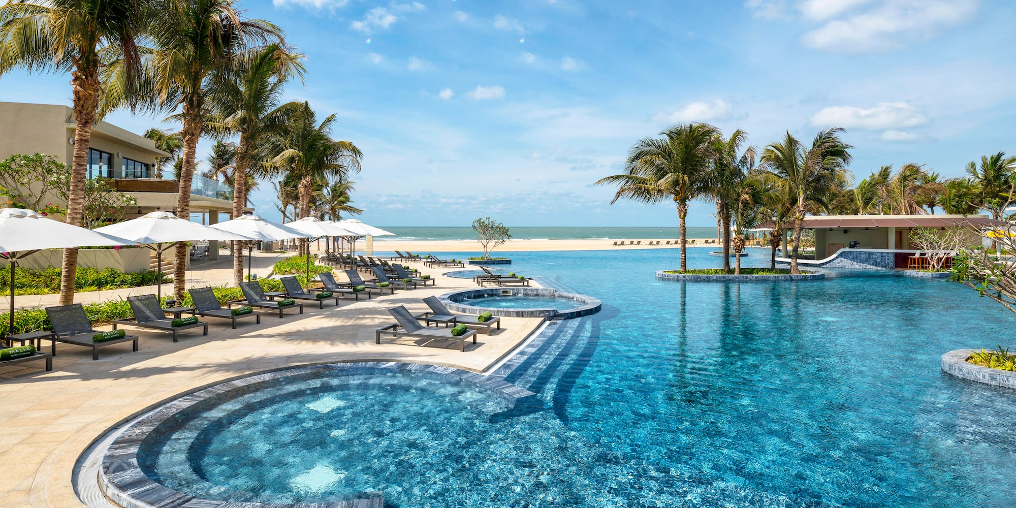 a pool with lounge chairs and palm trees on a beach