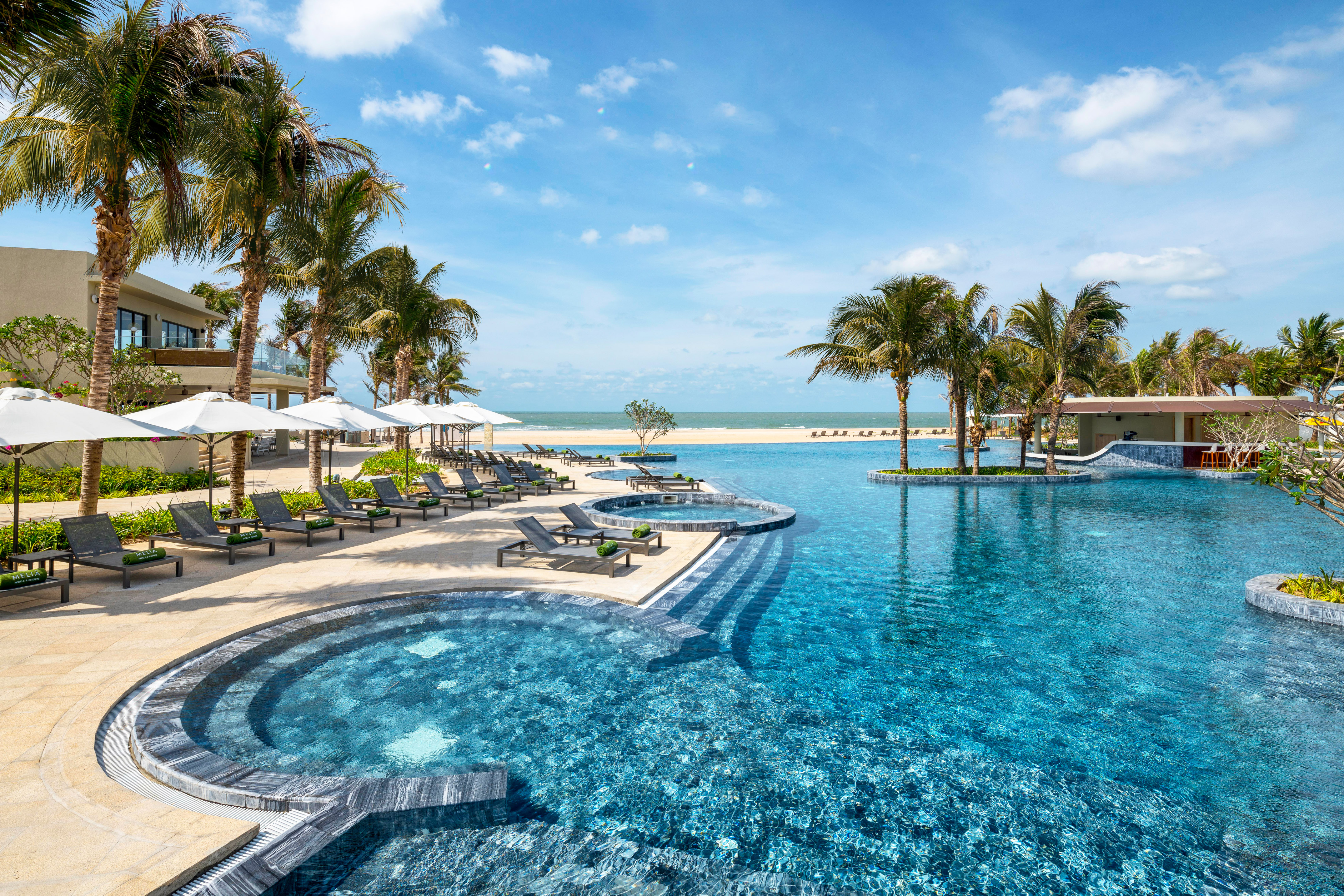 a pool with lounge chairs and palm trees on a beach