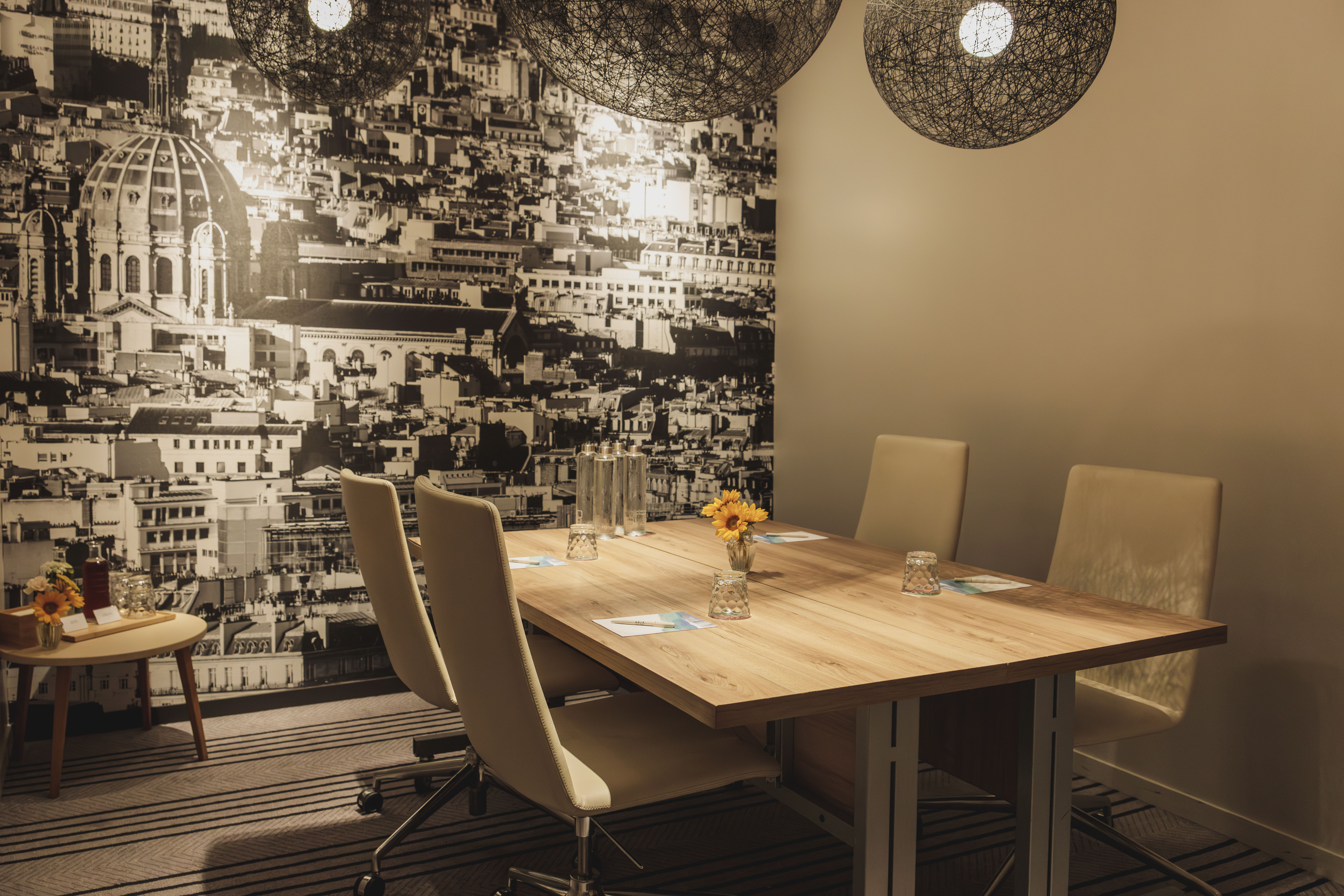 Conference room with cityscape mural, wooden table, and beige chairs.