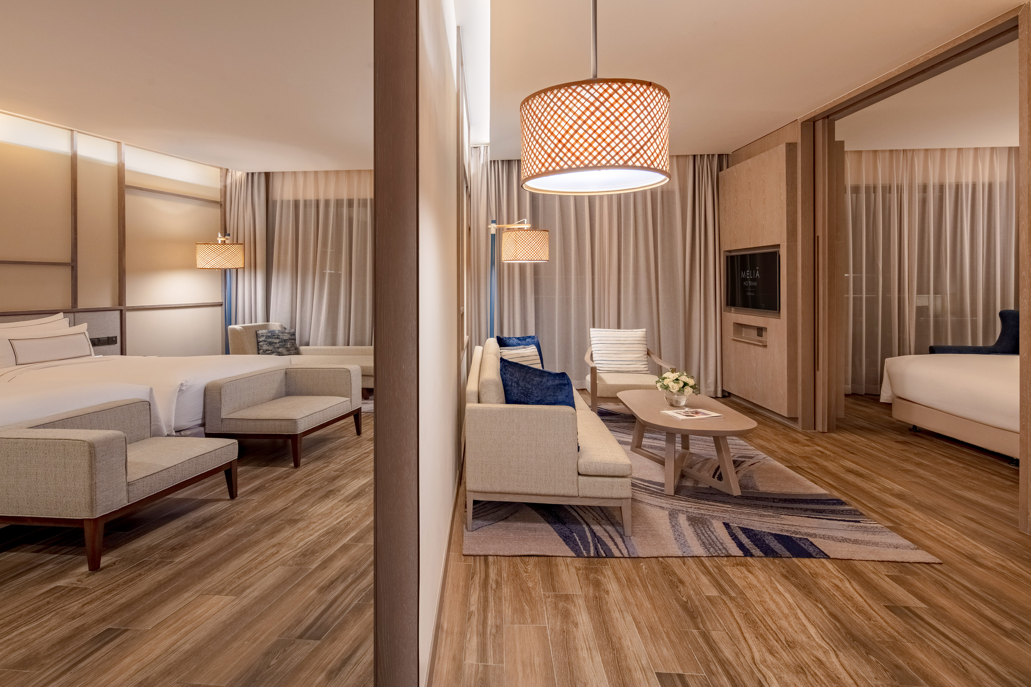 Meliá Ho Tram hotel suite with modern living area, bedroom, and wood flooring.