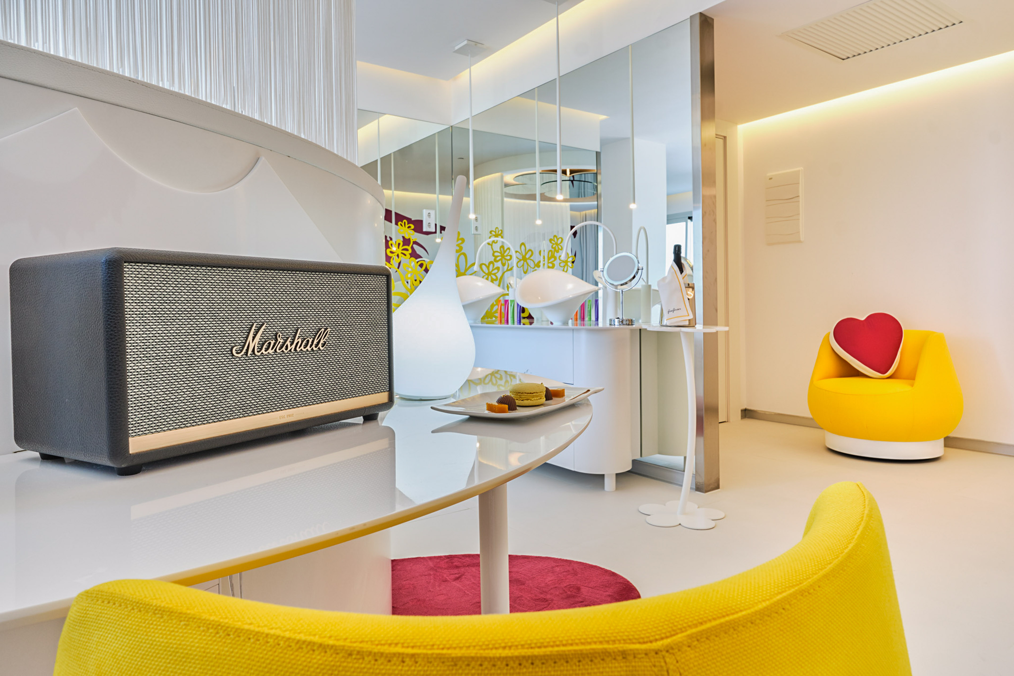 Marshall speaker on white desk in modern luxury room with yellow armchairs.