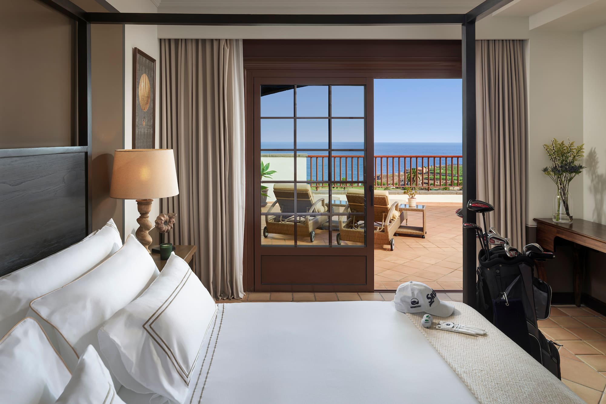 Suite de lujo con vistas al océano, balcón y bolsa de palos de golf.