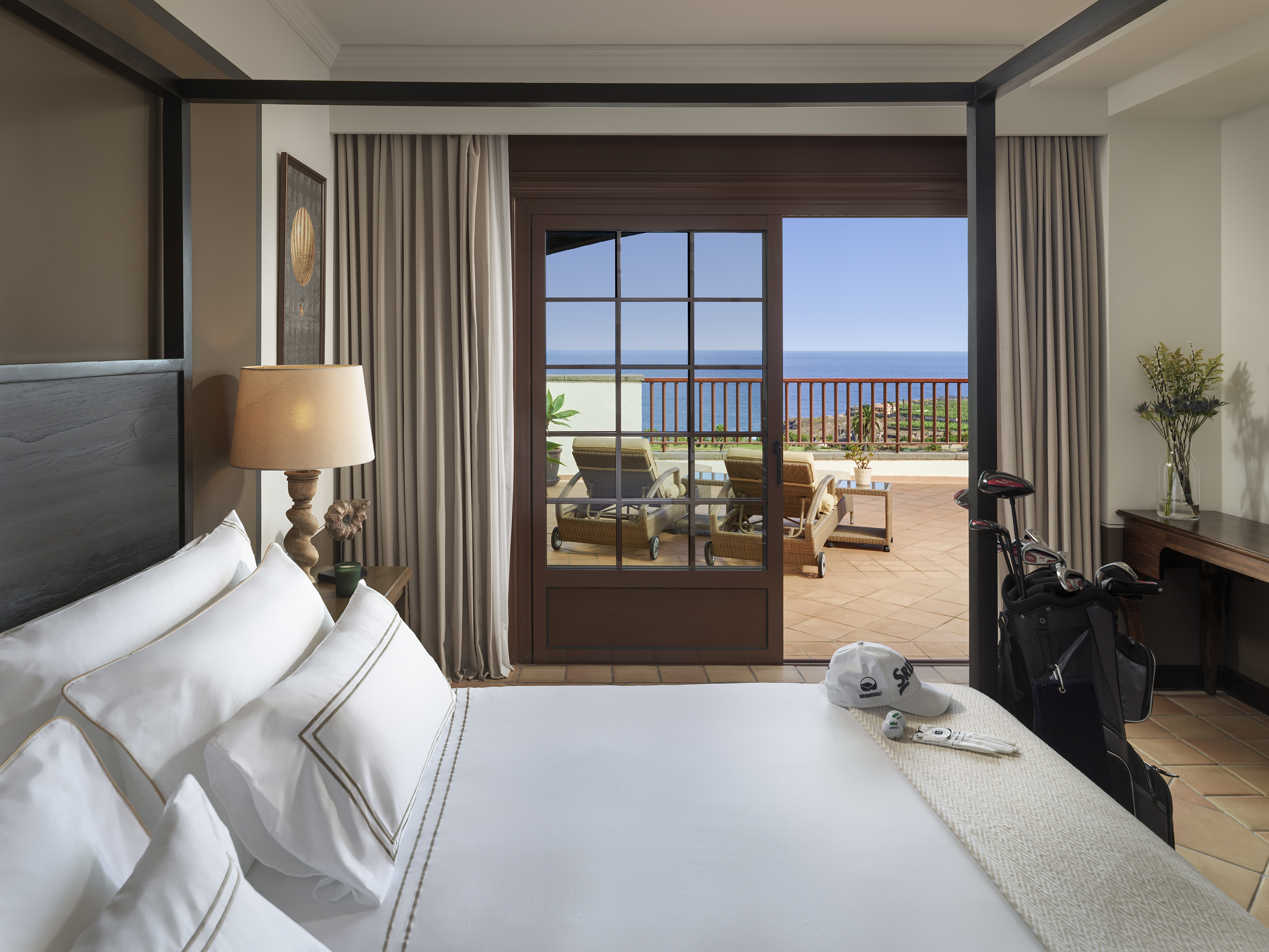 Suite de lujo con vistas al océano, balcón y bolsa de palos de golf.