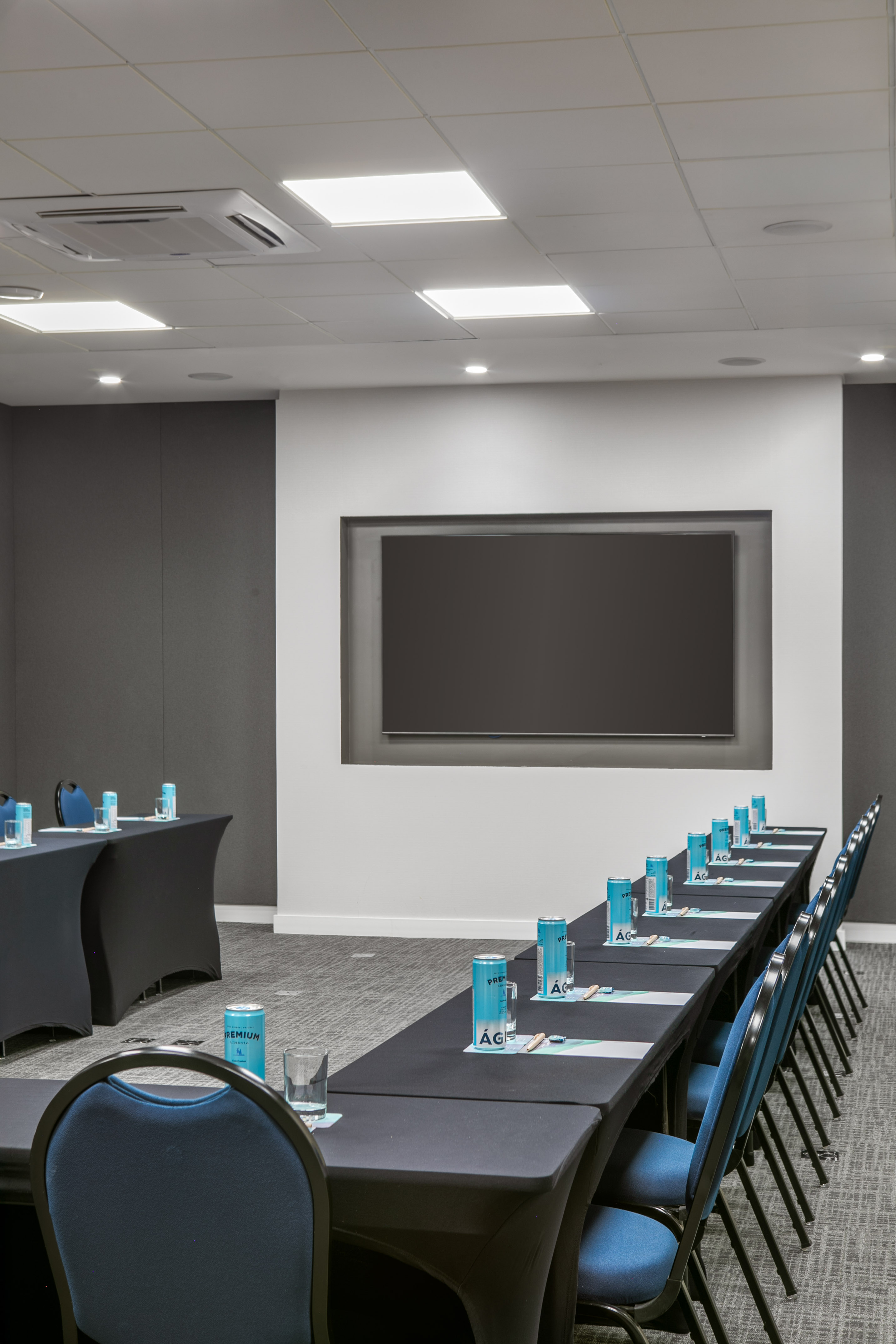 Modern U-shaped meeting room with blue chairs and large presentation screen.