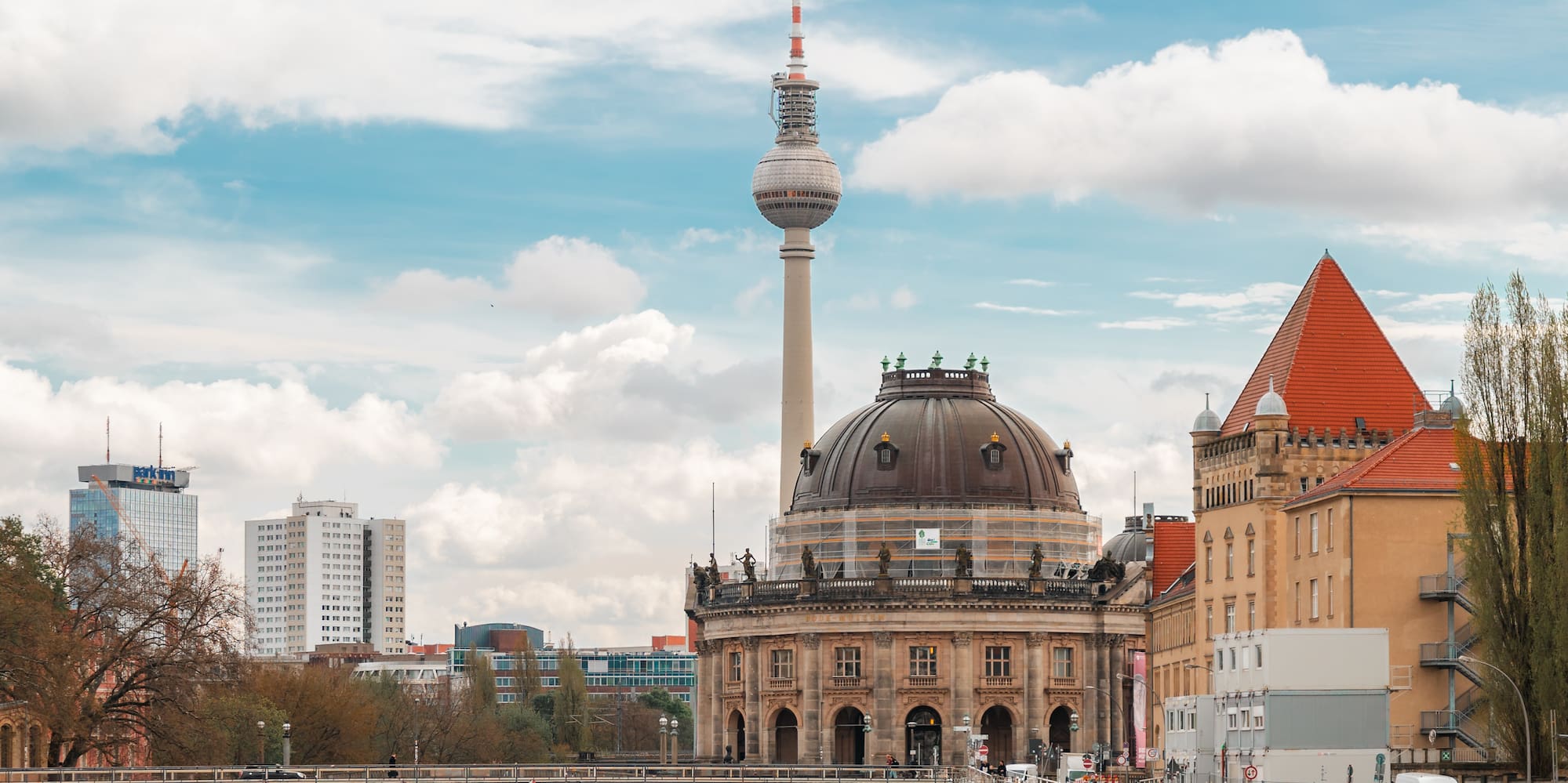 Berlin cityscape: Fernsehturm, Bode Museum, and Spree River with cruise boats.