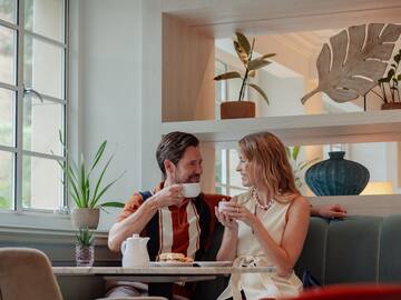 a man and woman sitting at a table with coffee cups