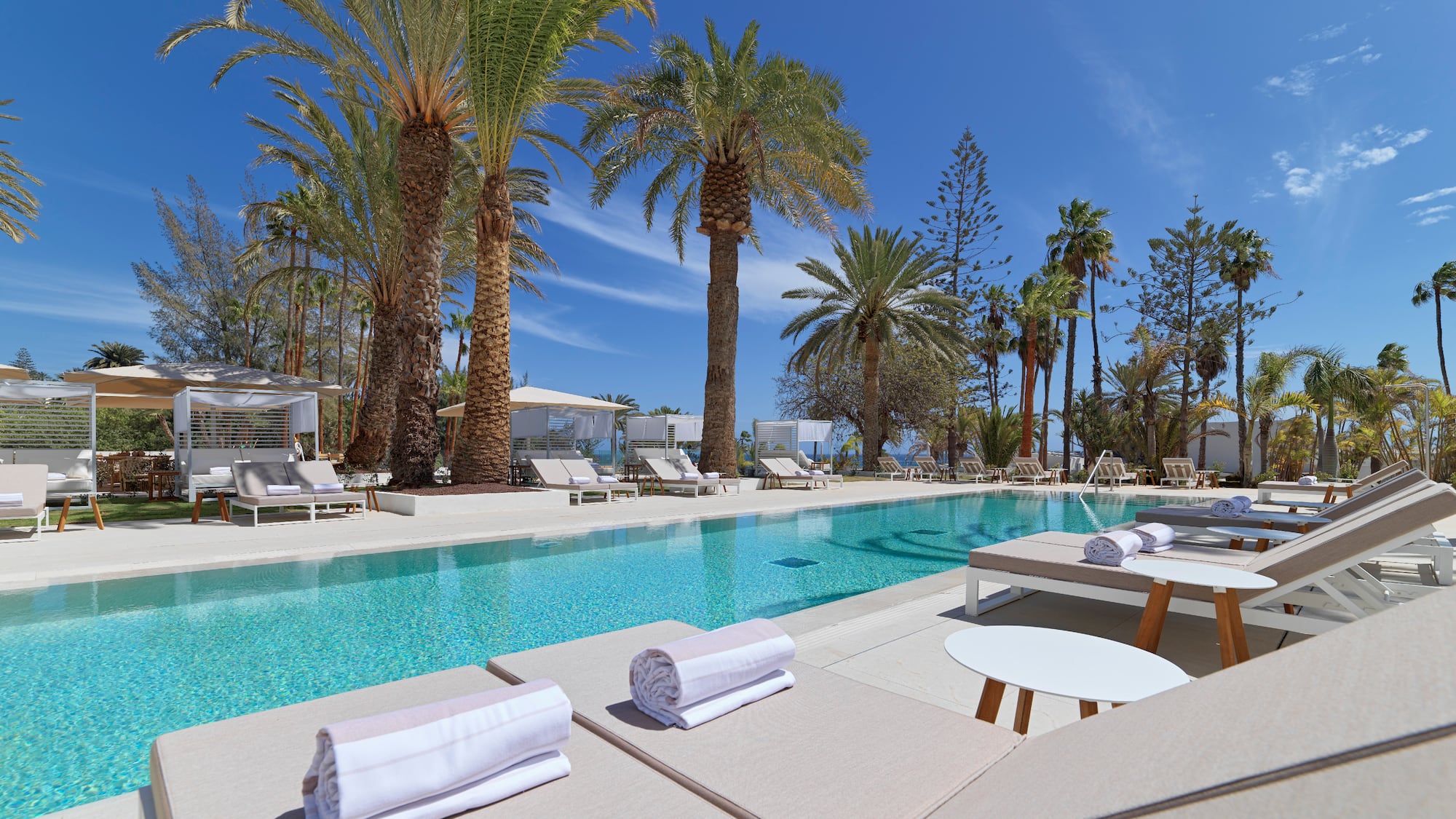 a pool with lounge chairs and tables and chairs
