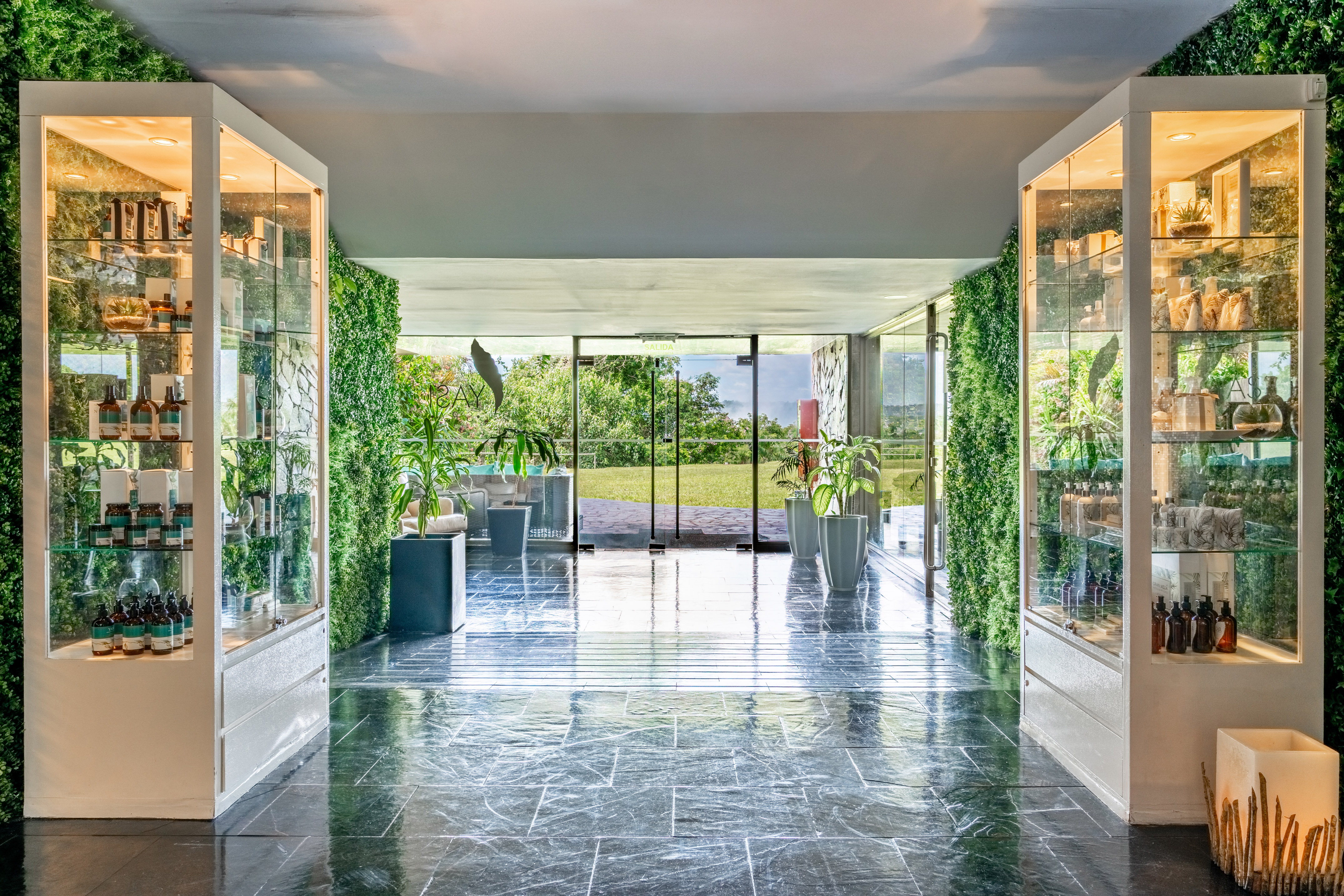 Modern spa entry with product displays, vertical gardens, and nature view.