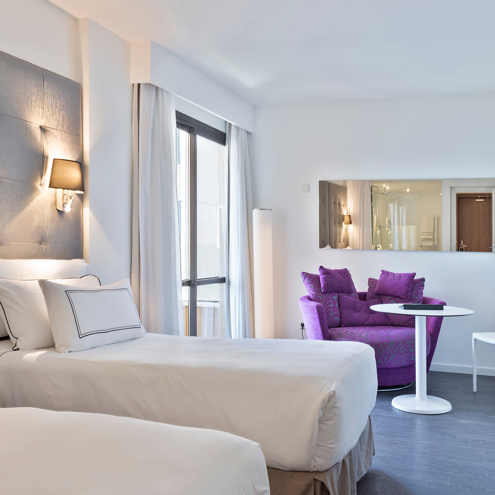 a room with two beds and a purple chair