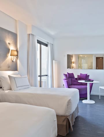 a room with two beds and a purple chair