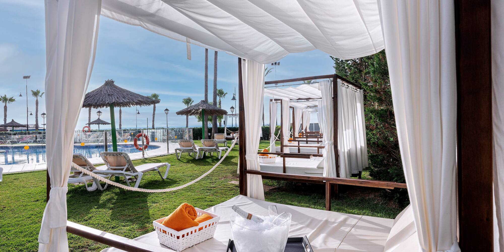 Poolside cabana with champagne, fruit, and daybed in a luxury resort.