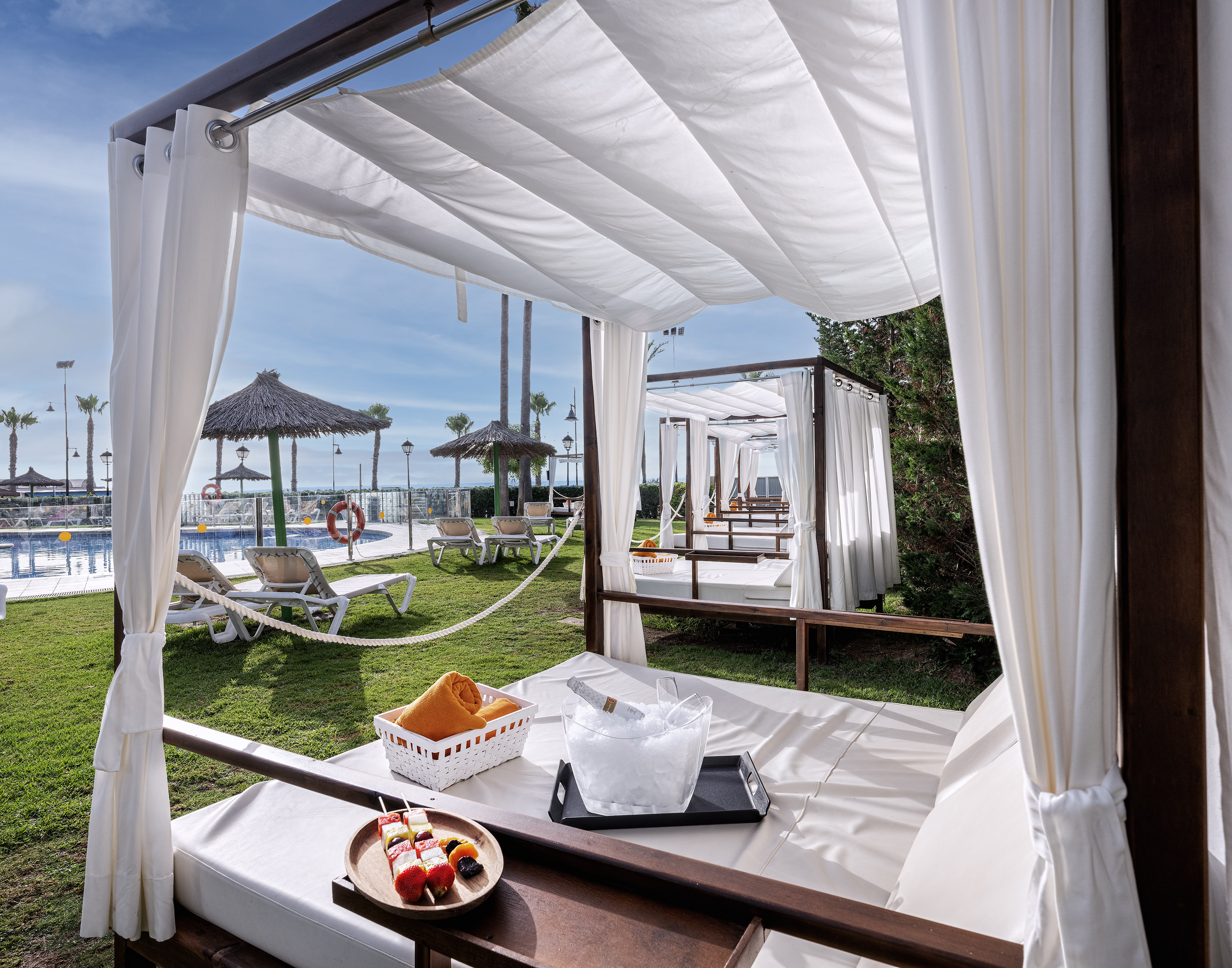 Poolside cabana with champagne, fruit, and daybed in a luxury resort.