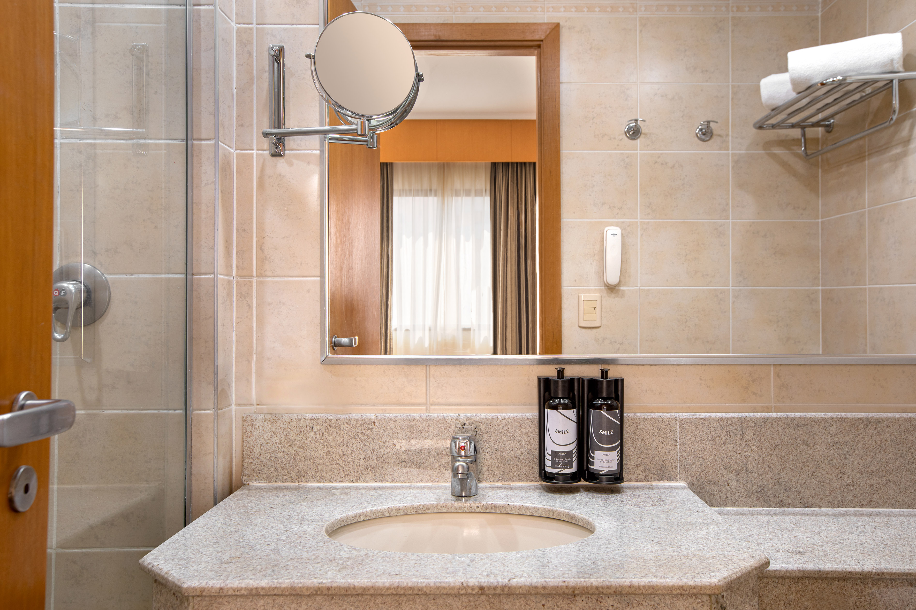 Hotel bathroom with granite vanity, sink, mirror, toiletries, and shower.