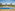 a pool with chairs and a beach and buildings
