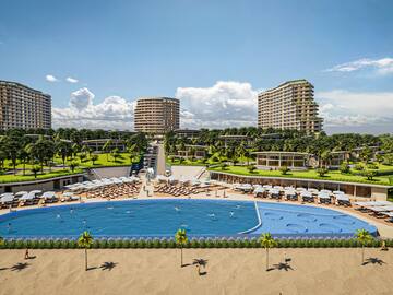 a pool with chairs and a beach and buildings