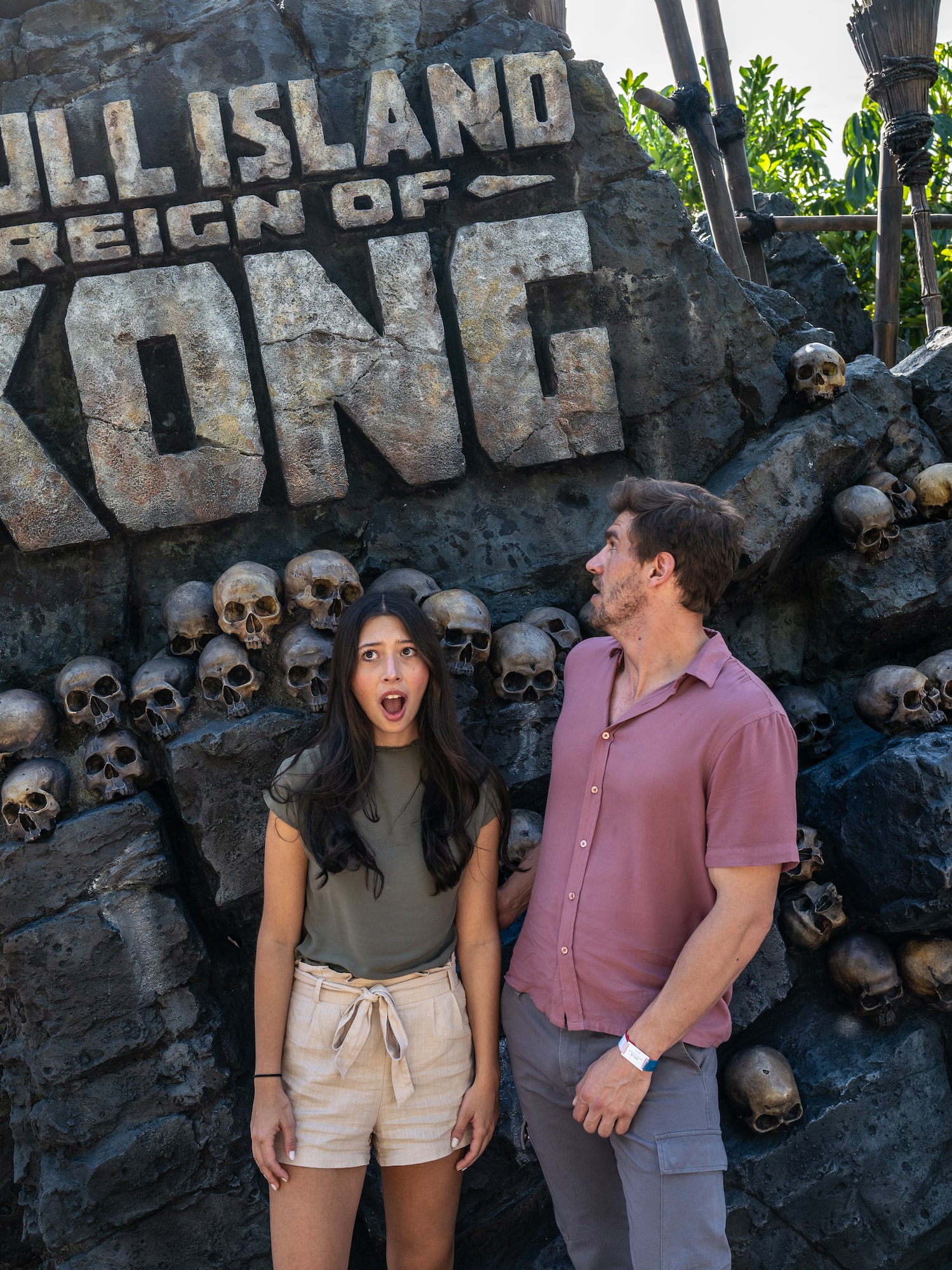a man and woman standing in front of a rock wall with skulls