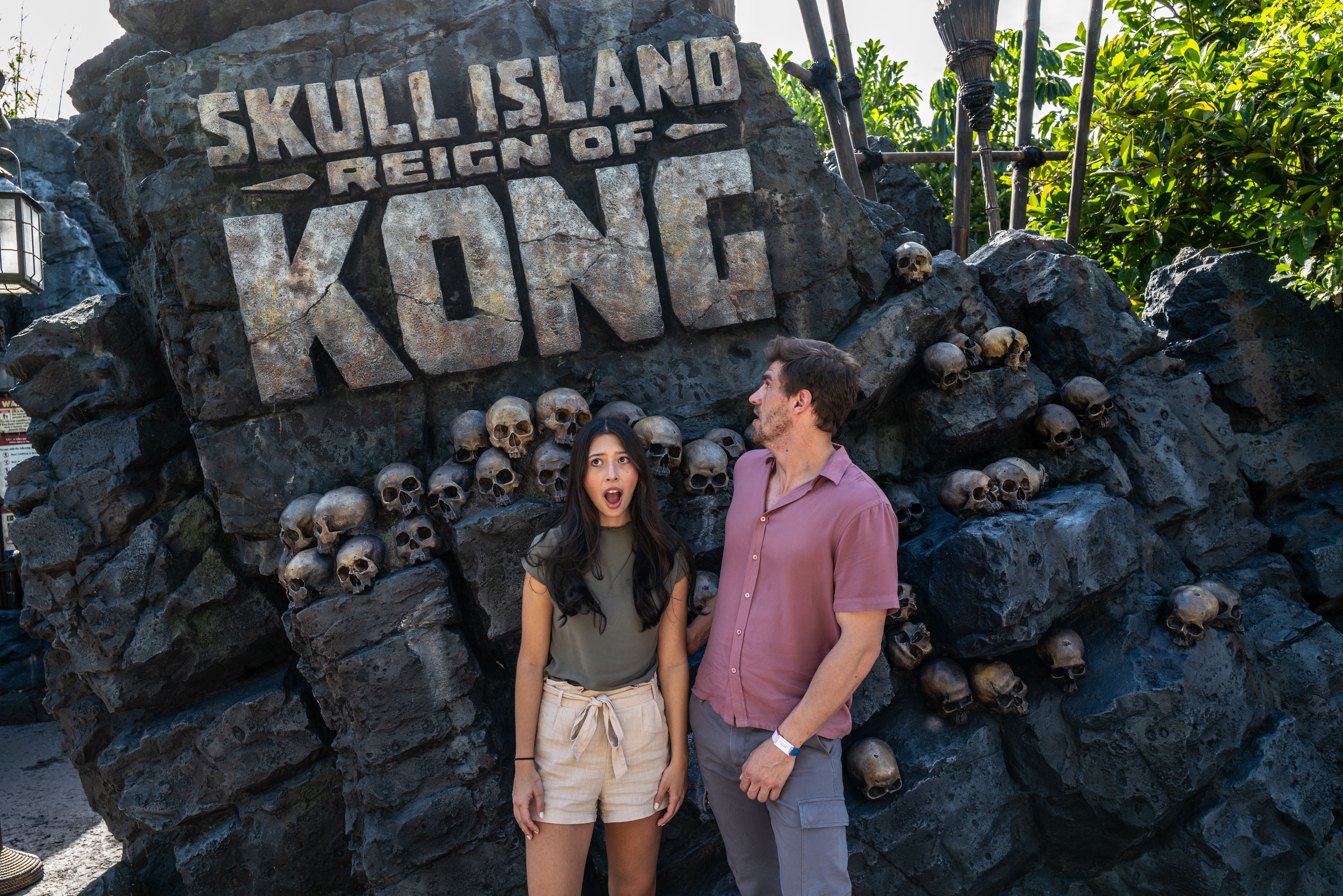 a man and woman standing in front of a rock wall with skulls