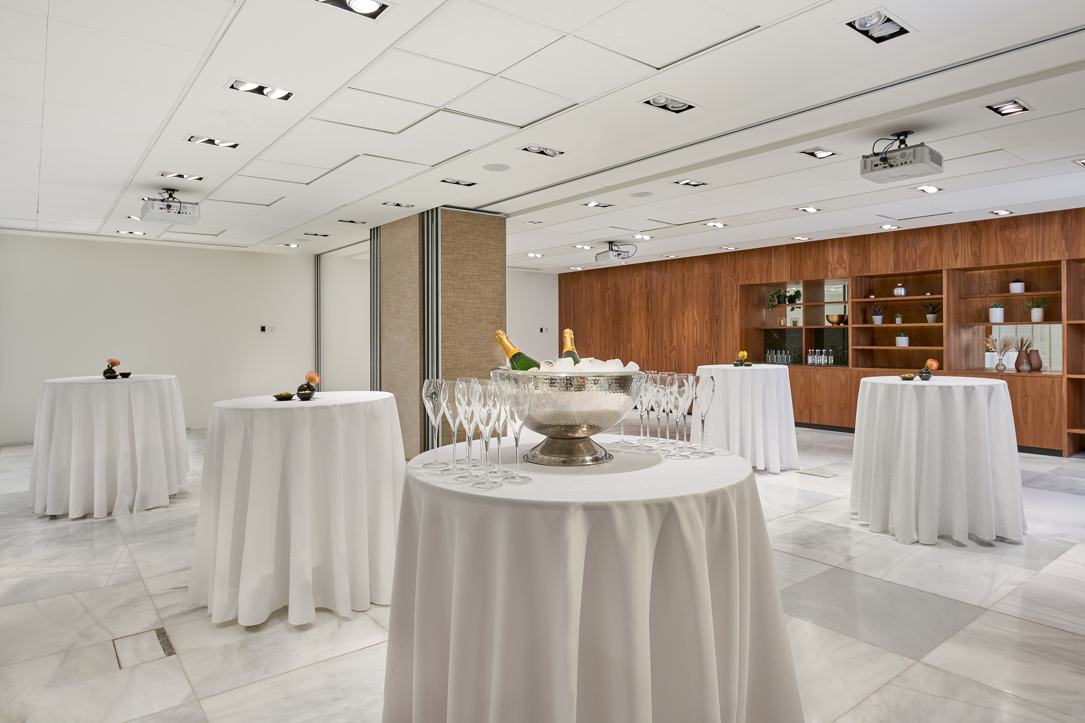 Modern event reception room with champagne, cocktail tables, and marble floor.