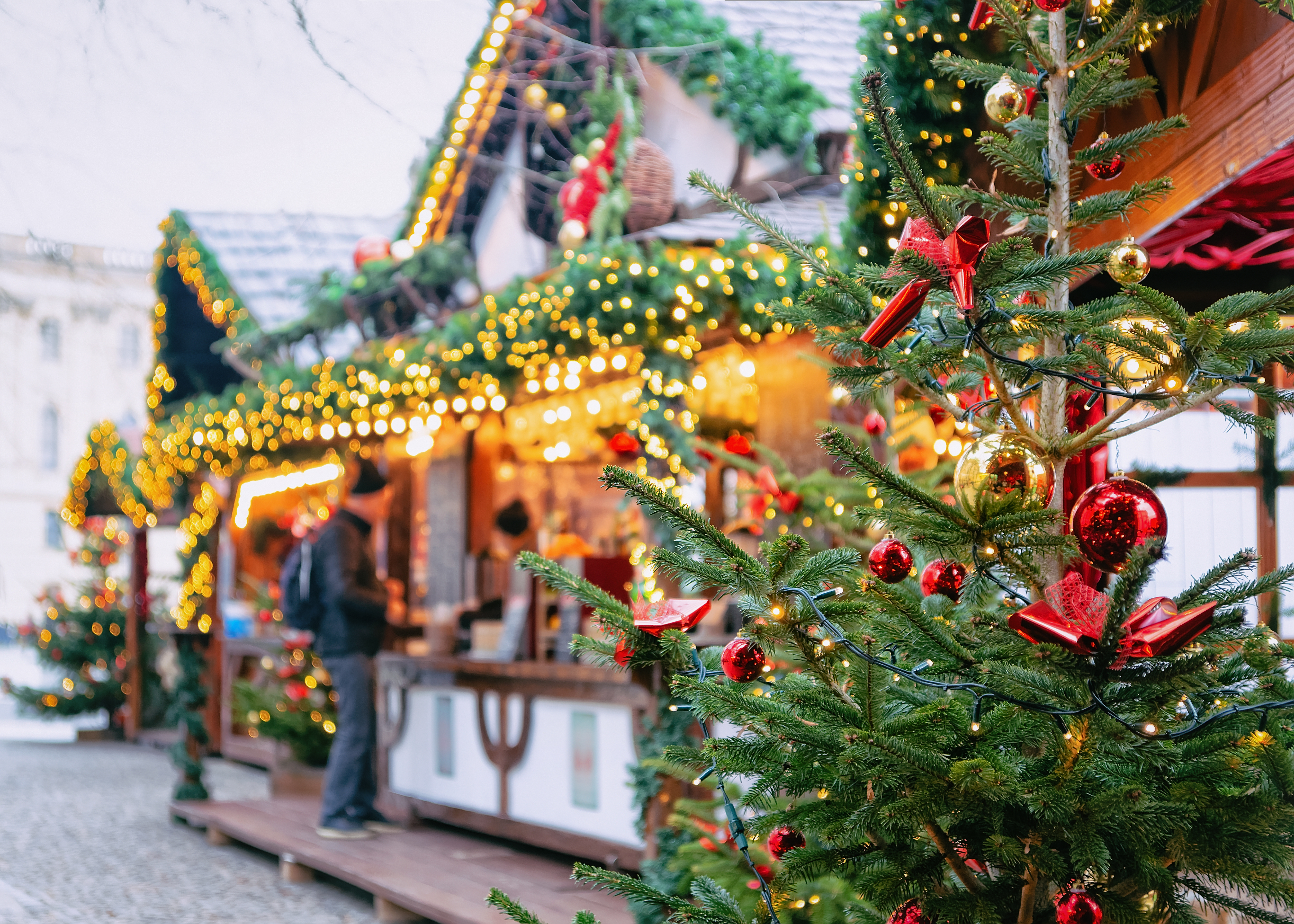 Christmas market with decorated tree, red and gold ornaments, glowing lights.