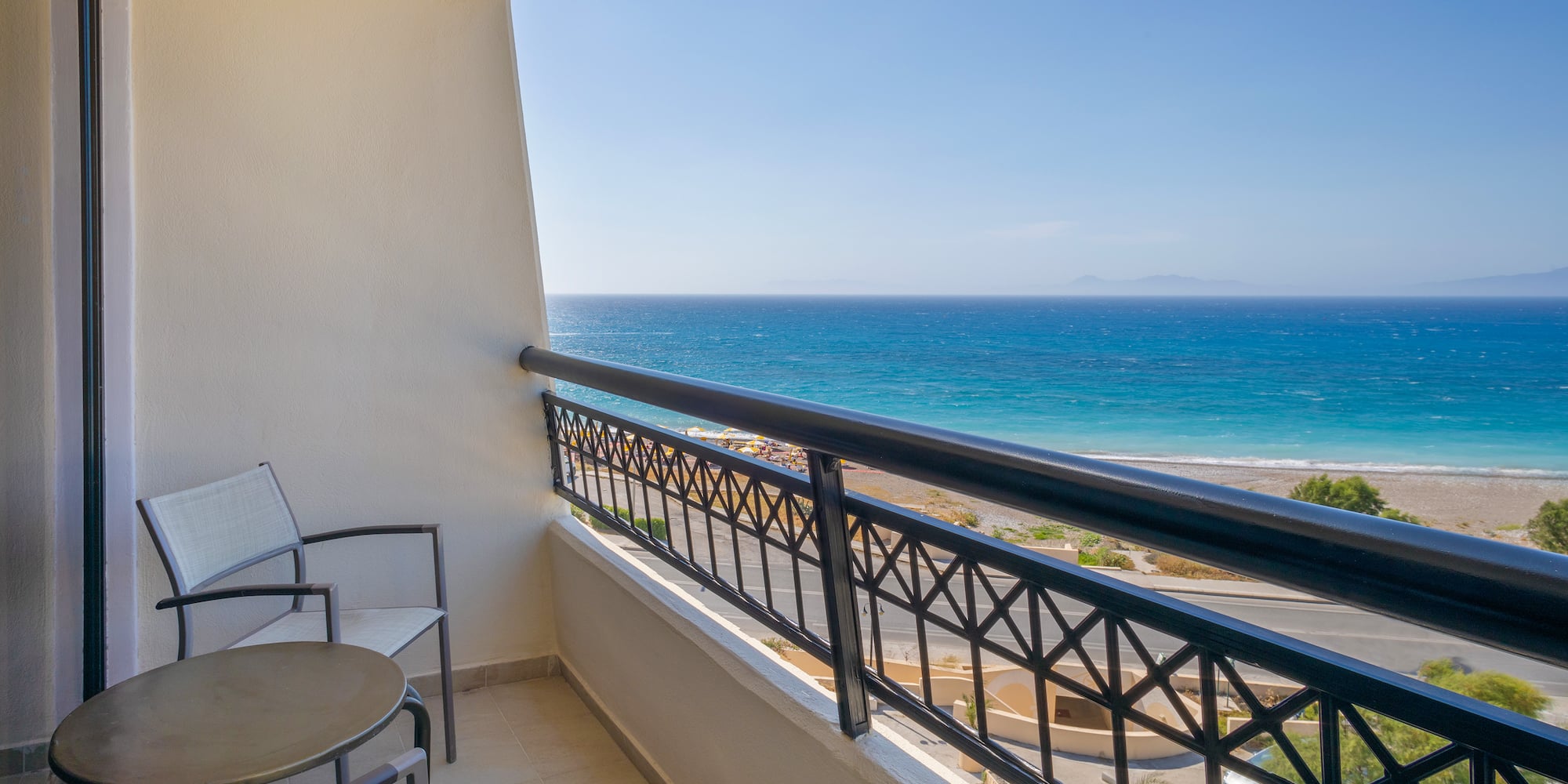 a balcony with chairs and a railing overlooking the ocean