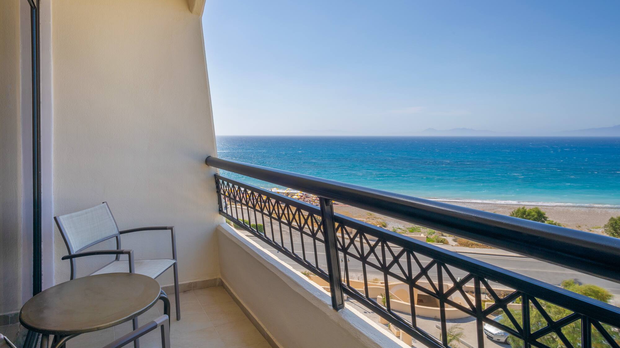 a balcony with chairs and a railing overlooking the ocean