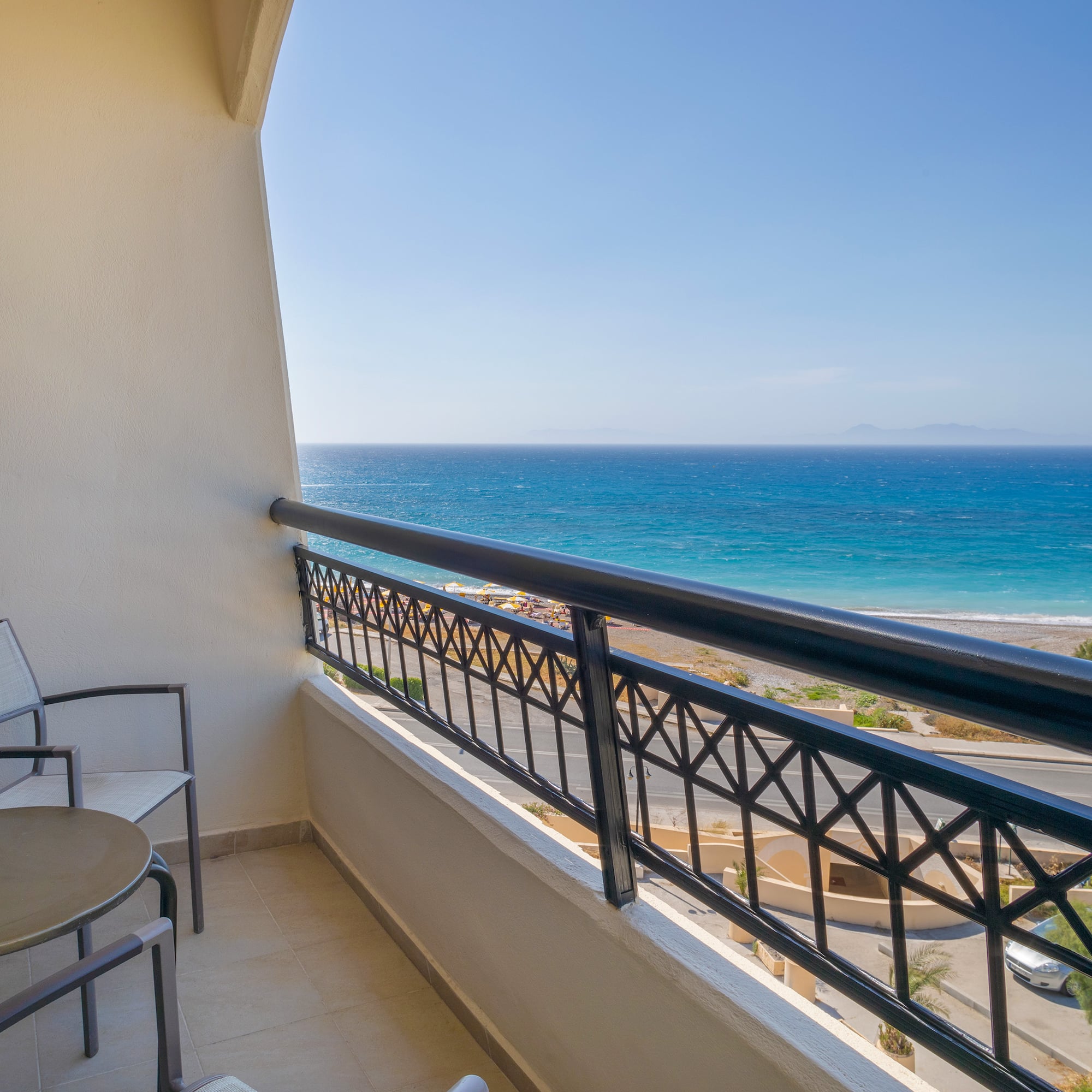 a balcony with chairs and a railing overlooking the ocean